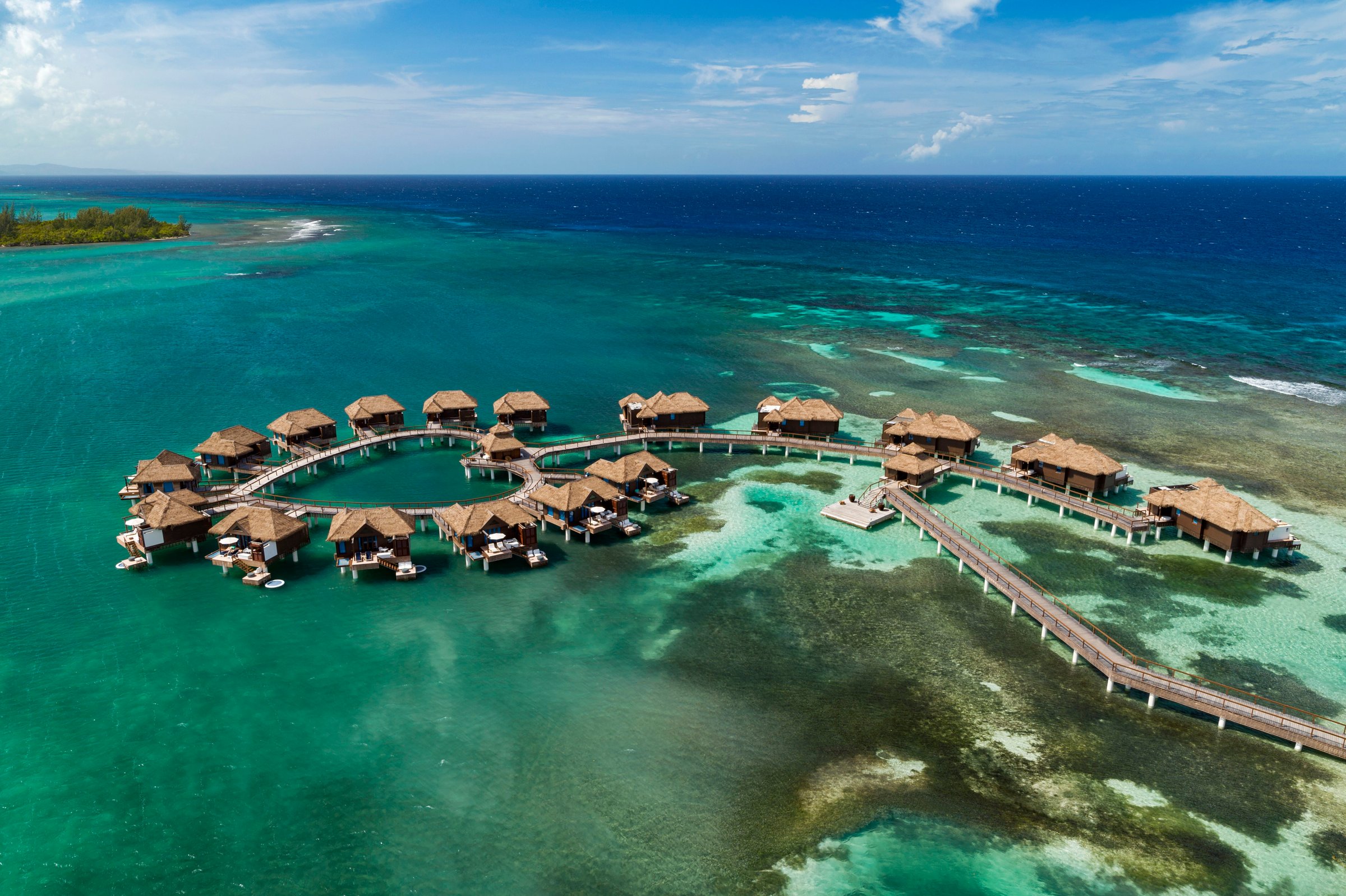 Aerial of over-water villas and boardwalk above the reef.