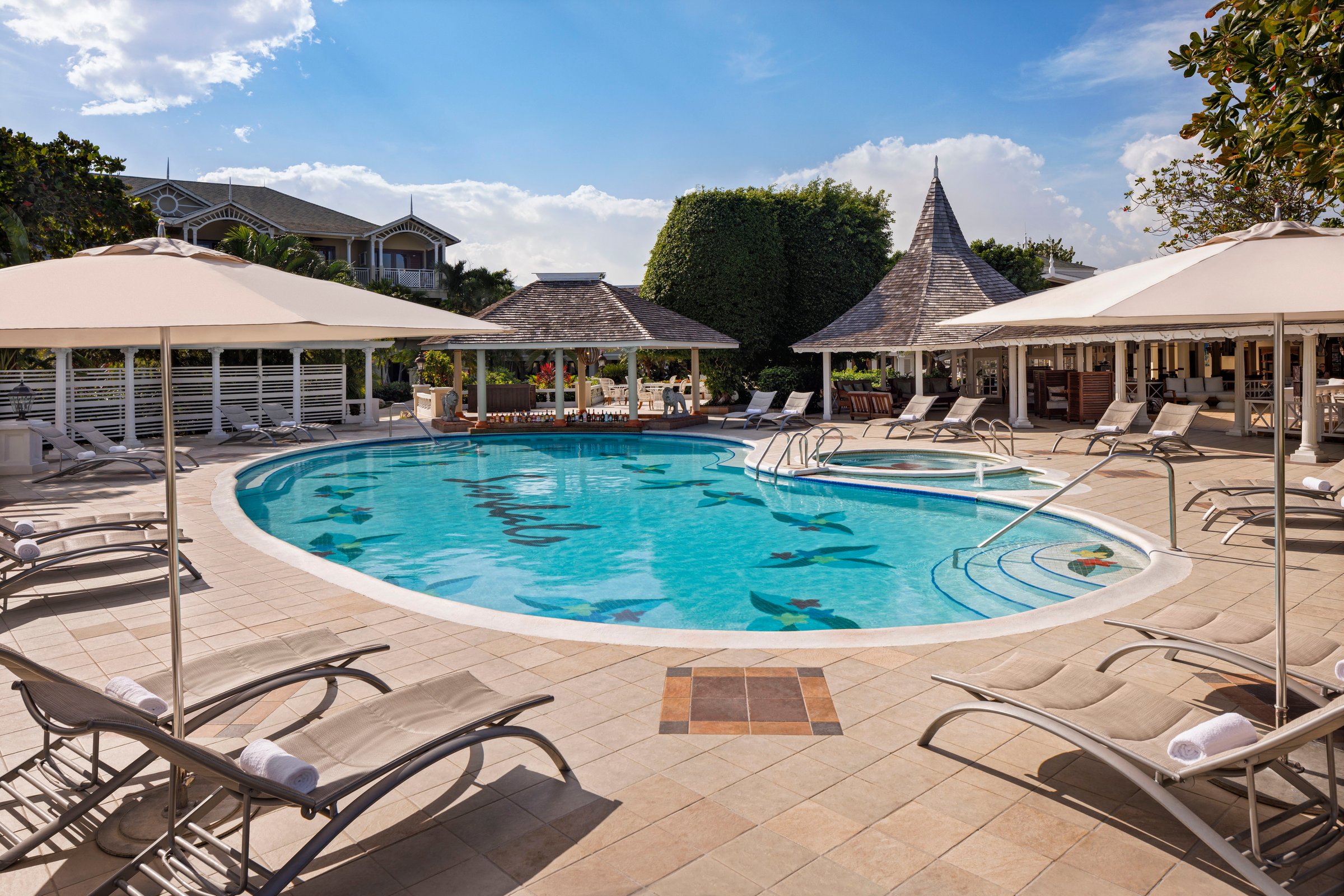 Main pool with mosaic floor, umbrellas, loungers and gazebos.