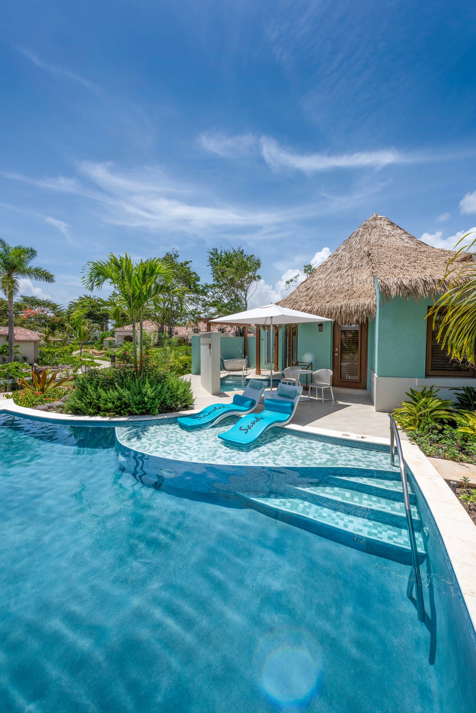 Swim-up suite pool with in-water loungers and a thatched cabana.