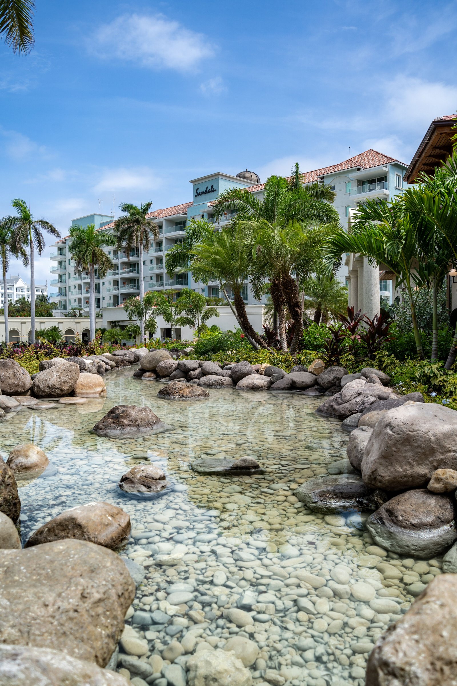 Rocky stream garden with clear water flowing past palms and the resort.