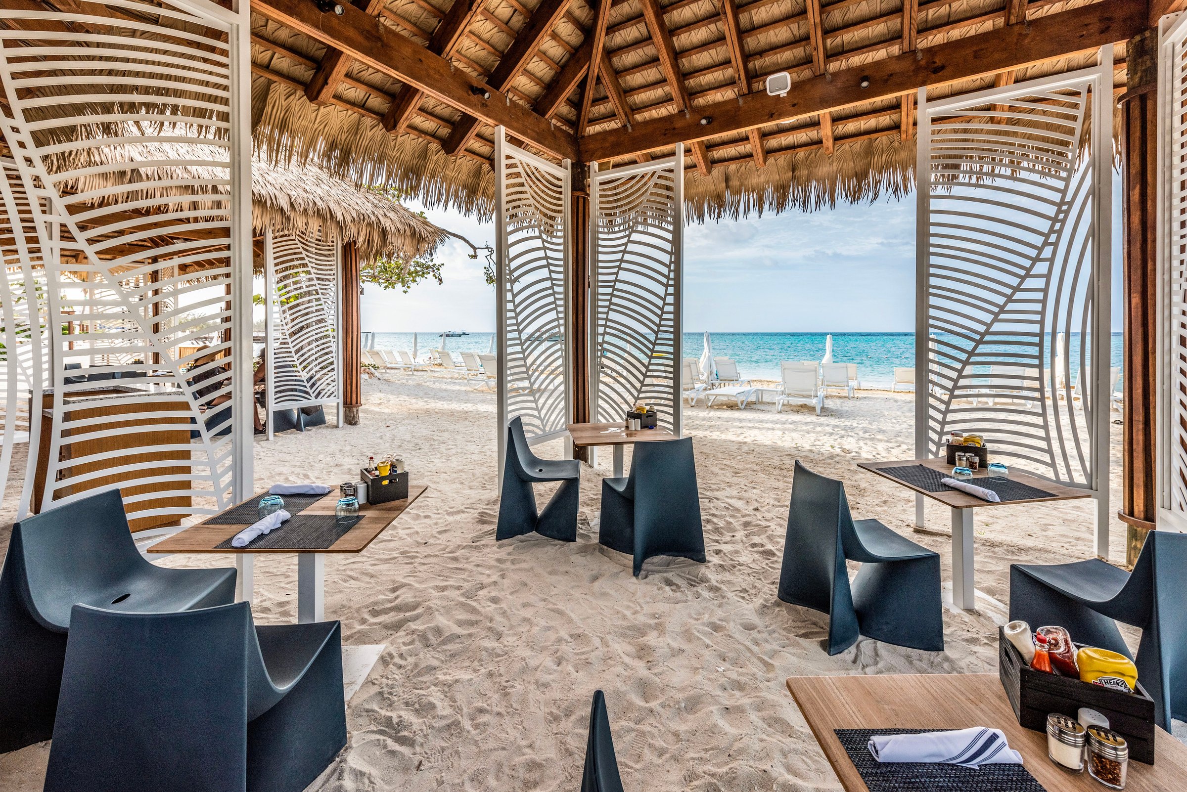 Galene beach restaurant with sculptural white screens and tables on the sand.