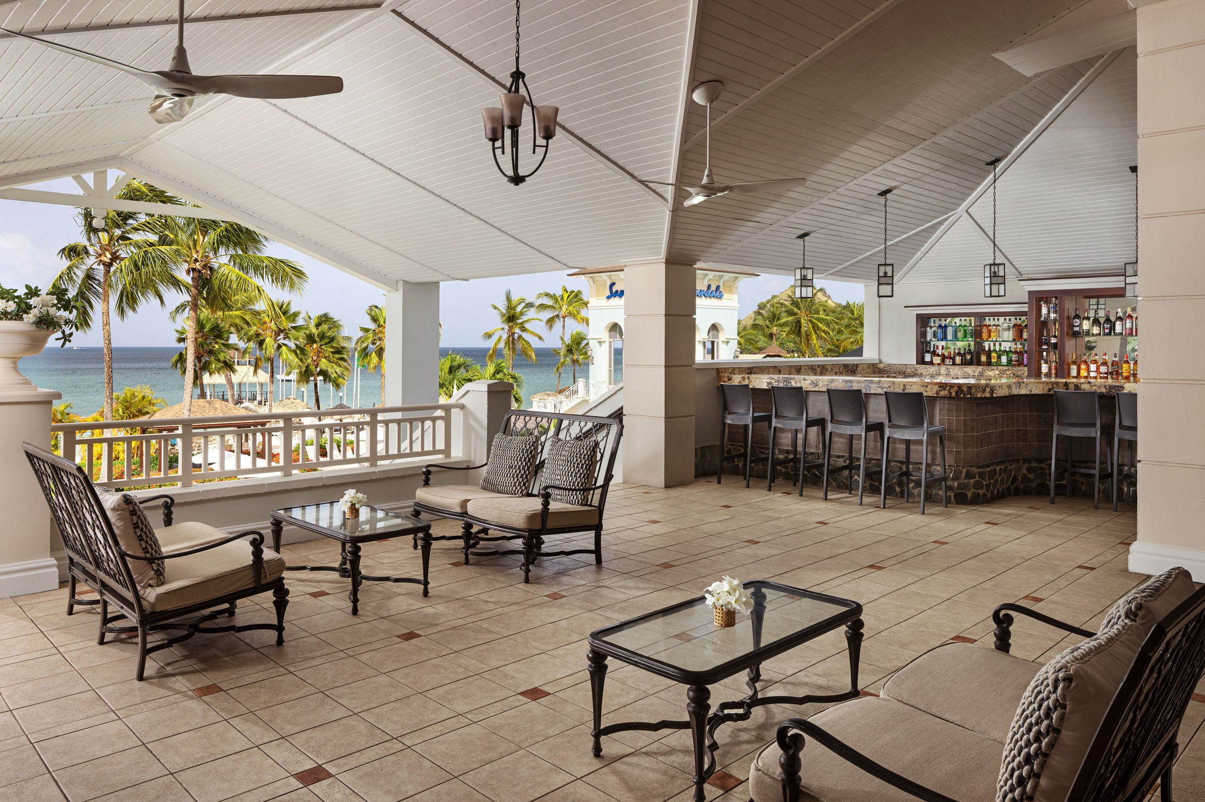 Open-air lobby bar with wrought-iron lounge seating and a view to the sea.