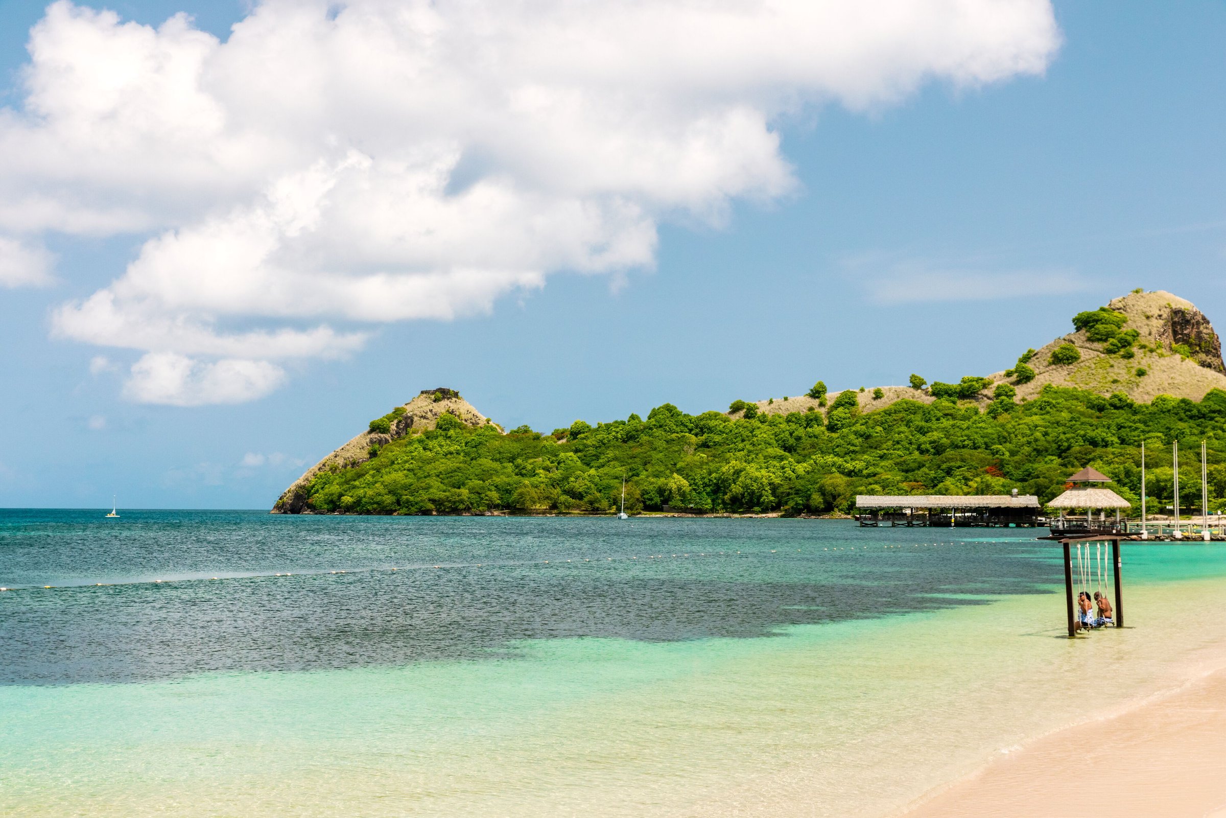Calm turquoise shallows with an ocean swing and Pigeon Island behind.