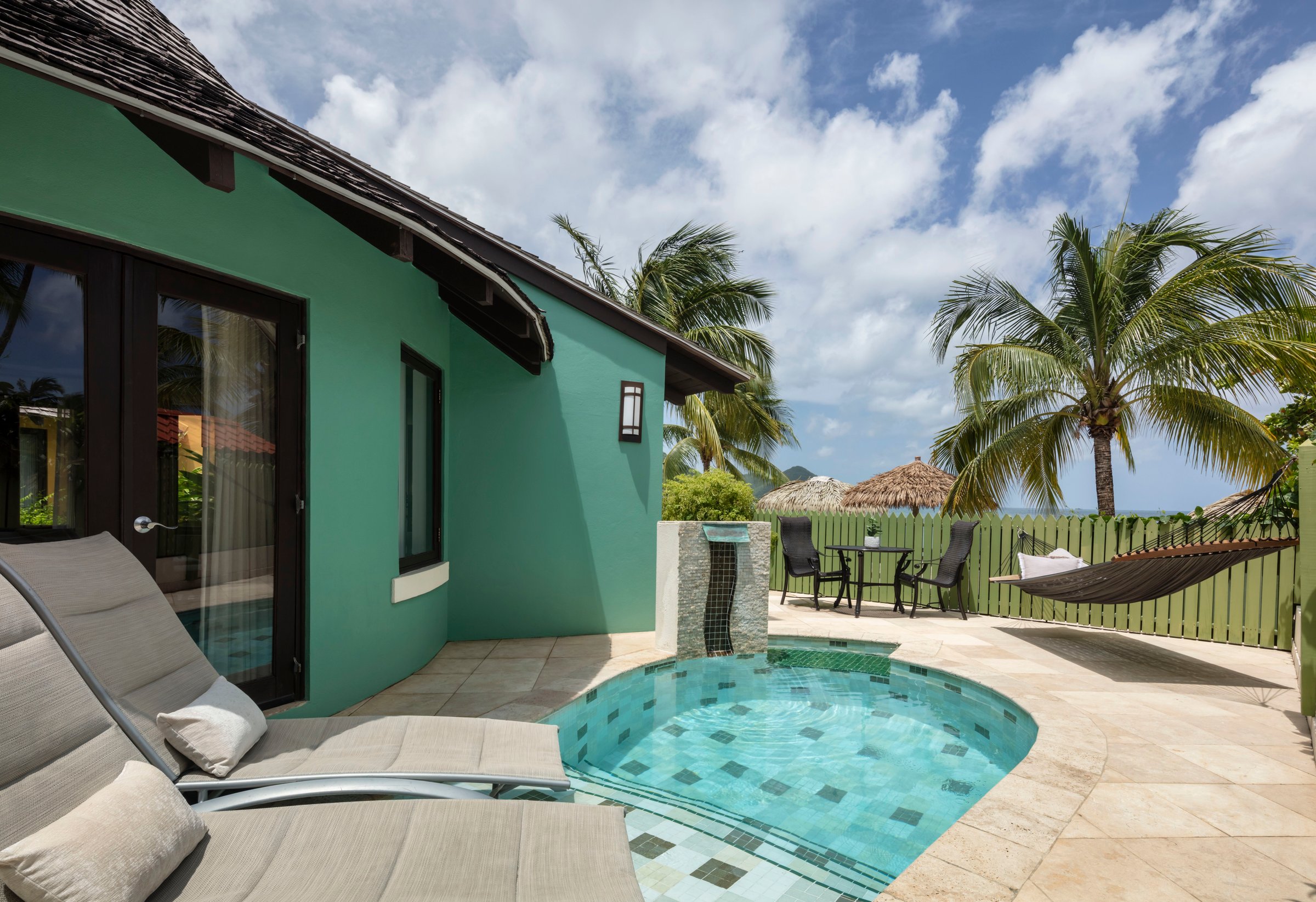 Private plunge pool and loungers outside a green butler suite with a hammock.