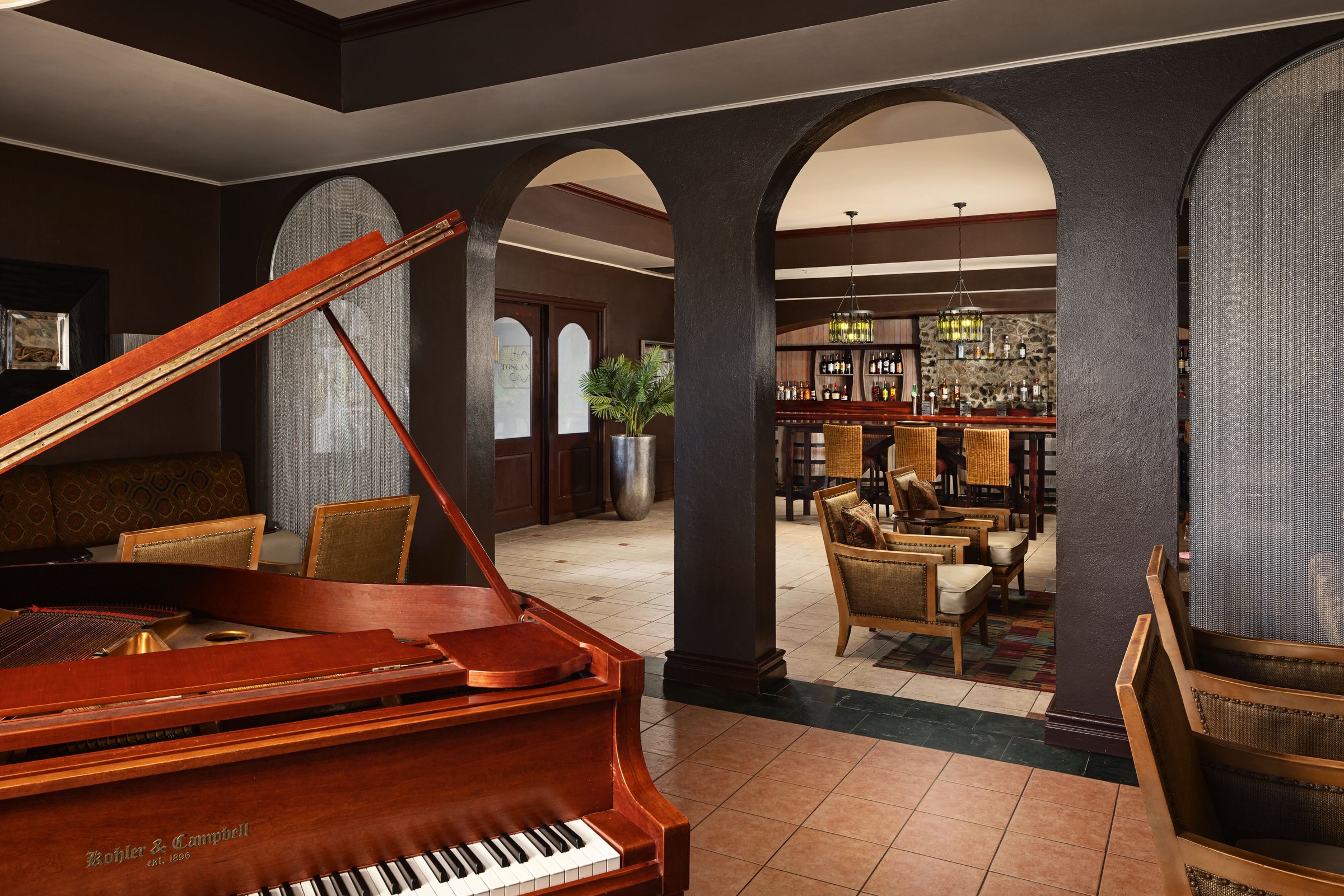 Piano Bar with a red grand piano, arched doorways and leather armchairs.