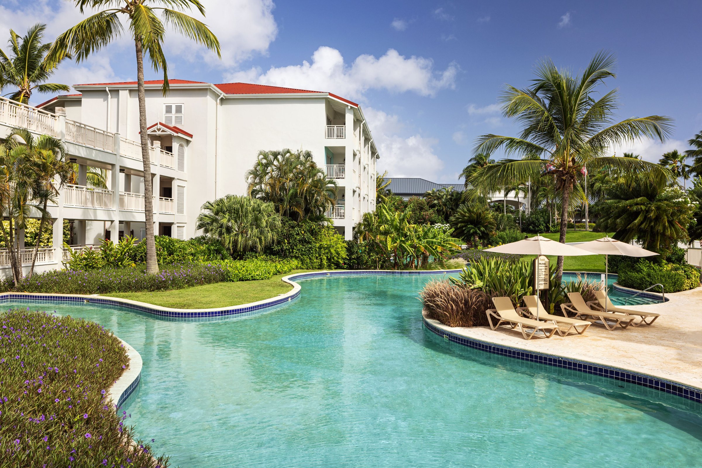 Lagoon pool curving past loungers and umbrellas beside the hotel wing.