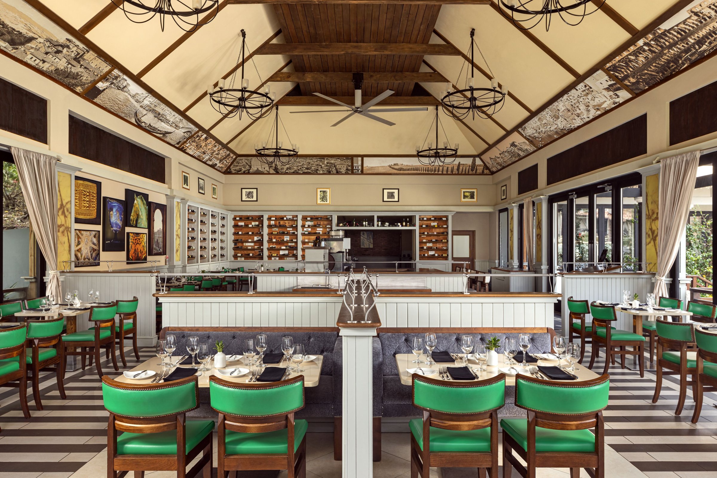 Cucina Romana dining room with green chairs and a vaulted timber ceiling.