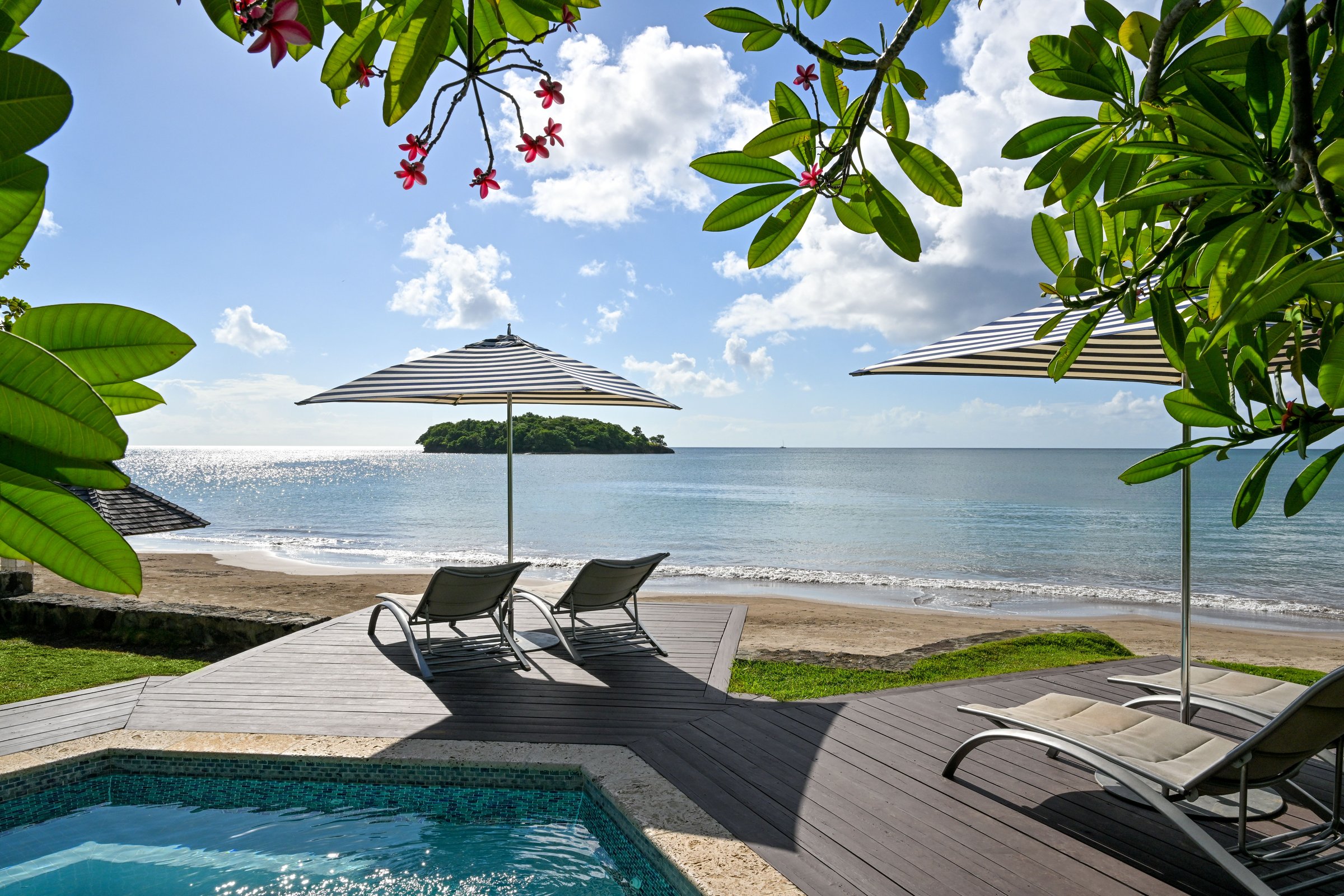 Beachside deck with a plunge whirlpool, loungers and striped umbrellas.