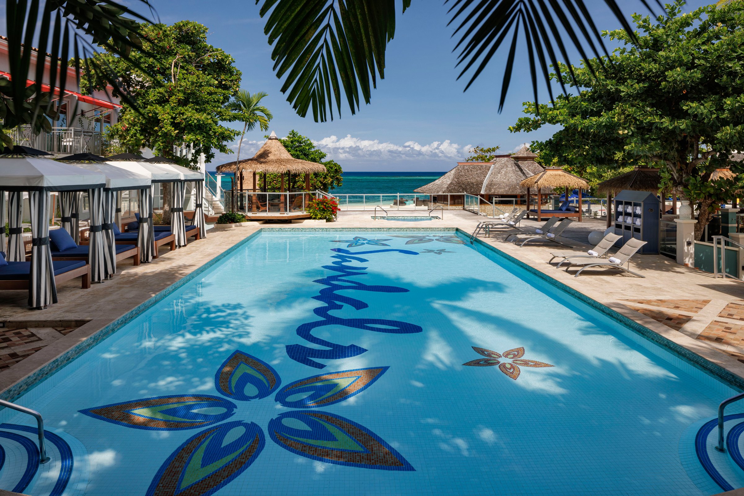 Main pool with the Sandals mosaic, cabanas and palms.