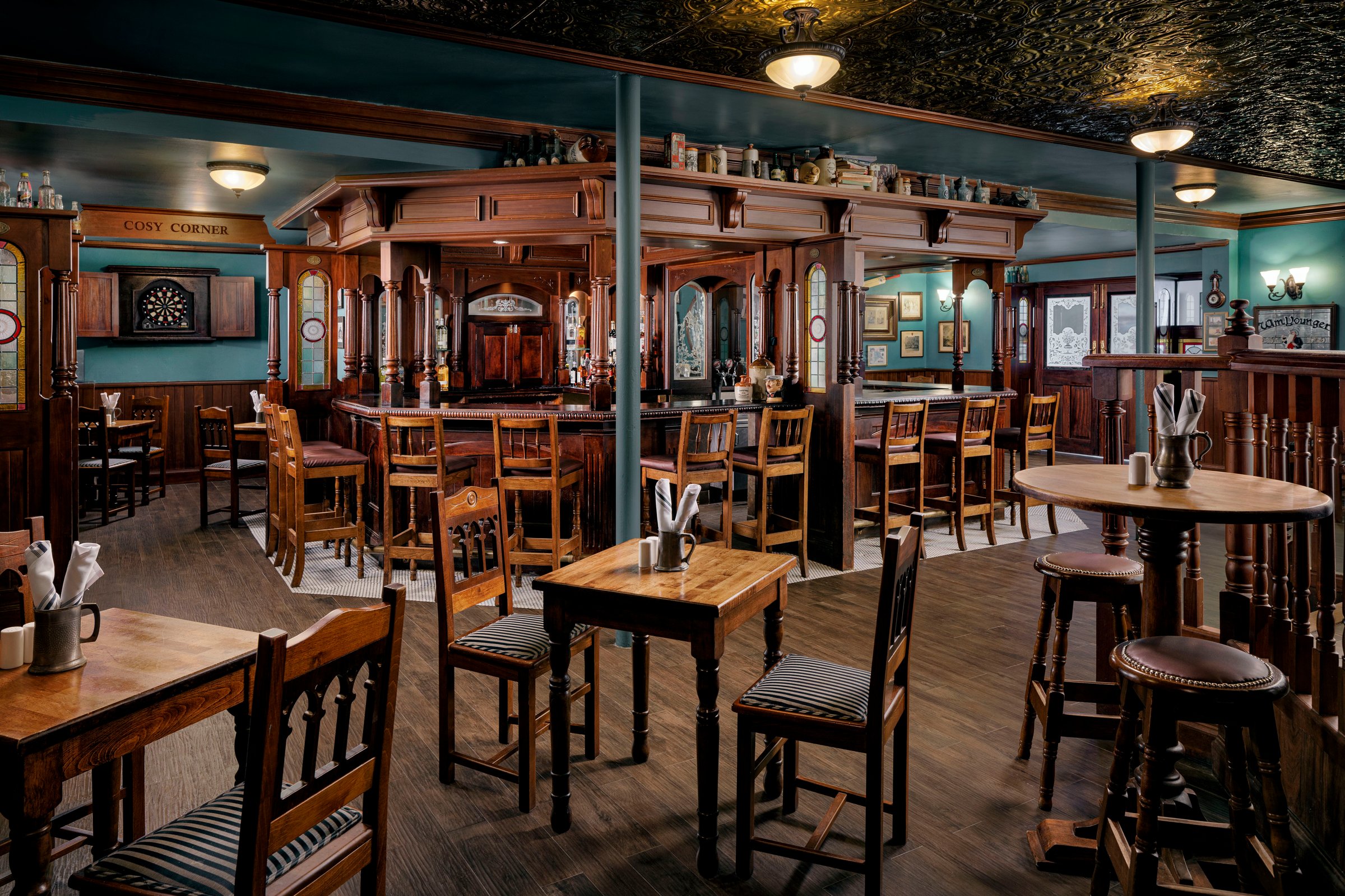 Cricketers pub interior with dark wood, bar stools and a dartboard.