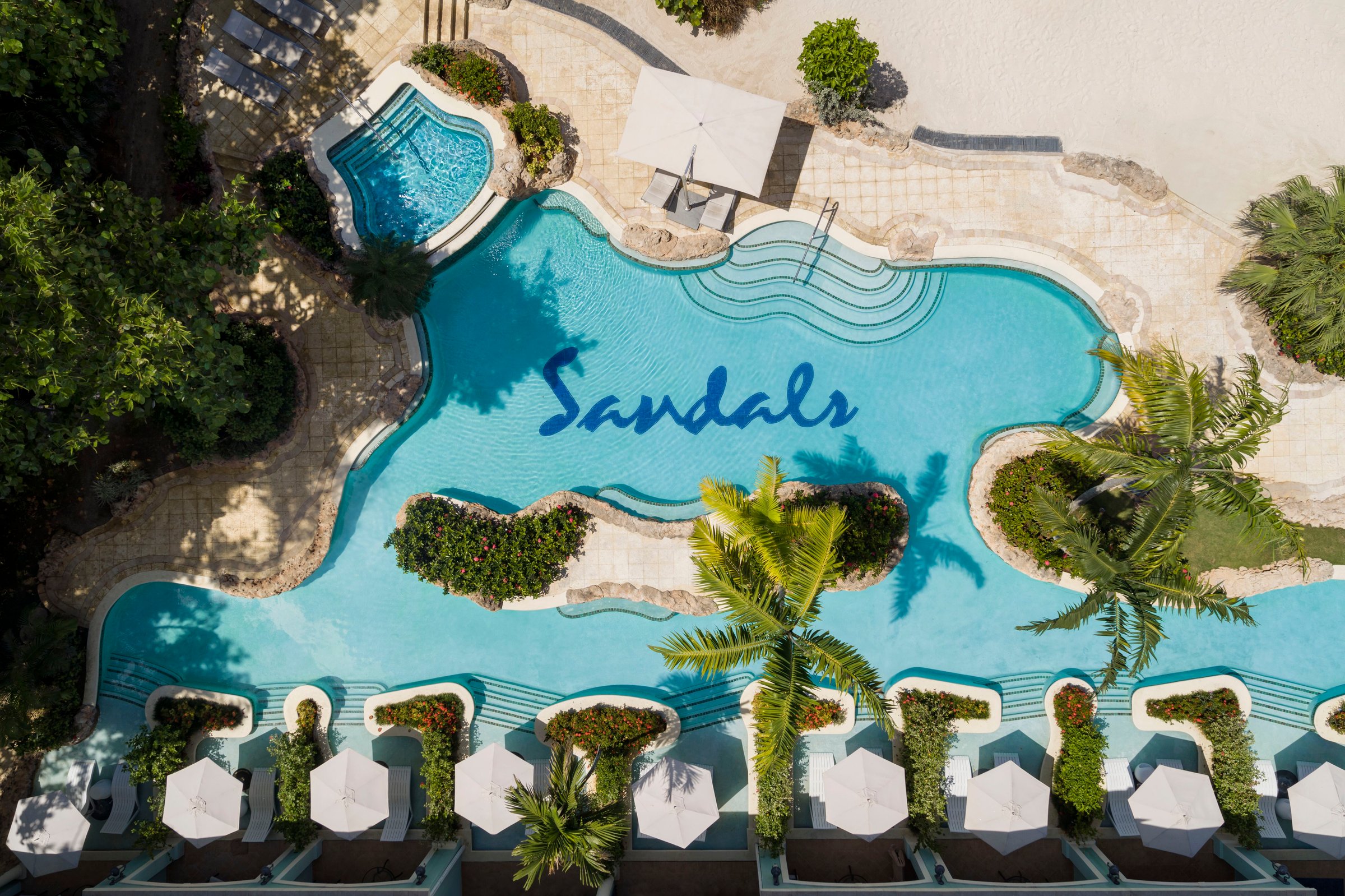 Top-down aerial of the Crystal Lagoon pool with the Sandals mosaic and cabanas.
