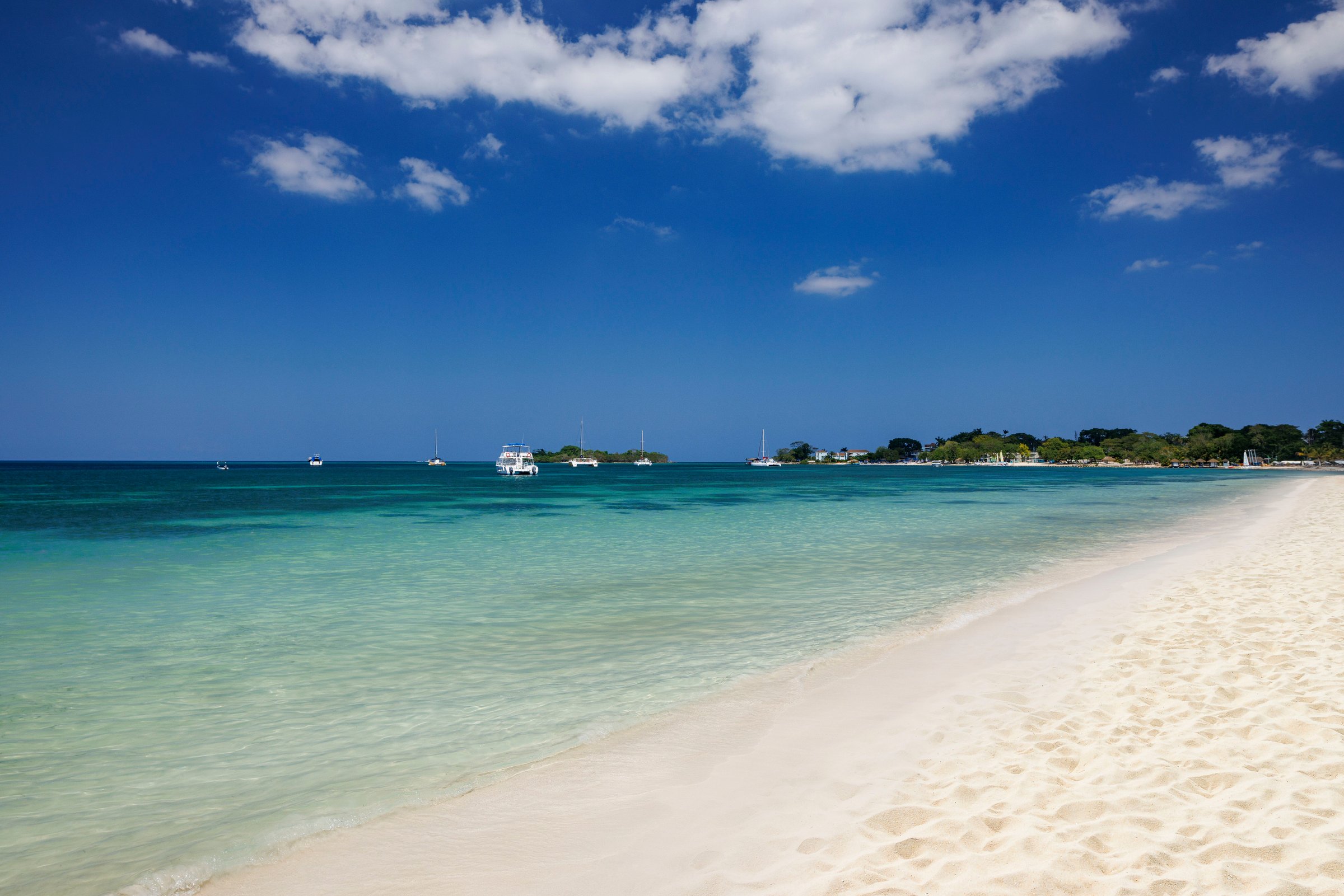 Seven Mile Beach curving away along clear turquoise shallows.