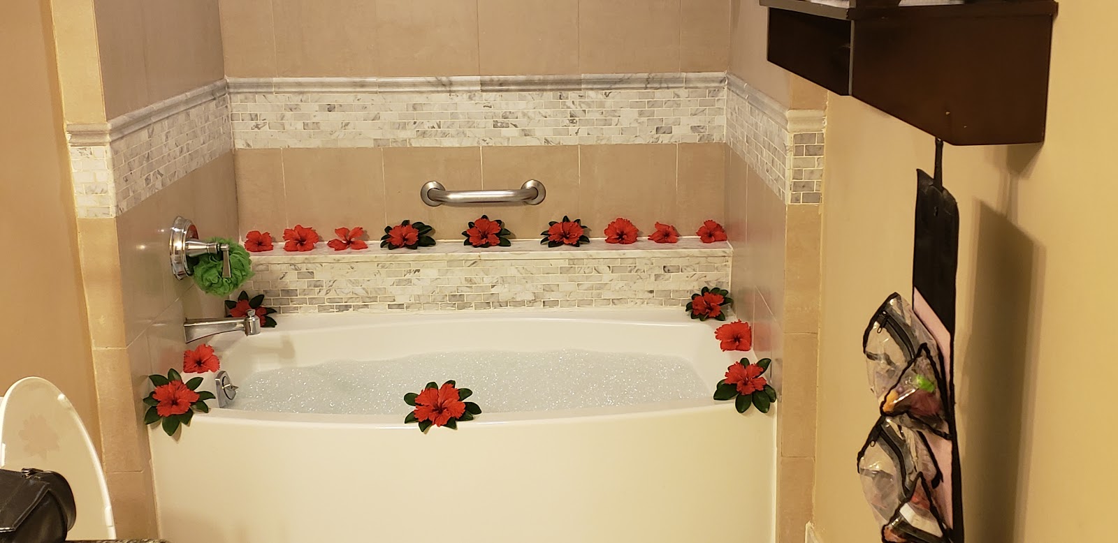 Bathtub decorated with red hibiscus flowers arranged along the rim and shelf at Sandals Ochi Beach Resort.