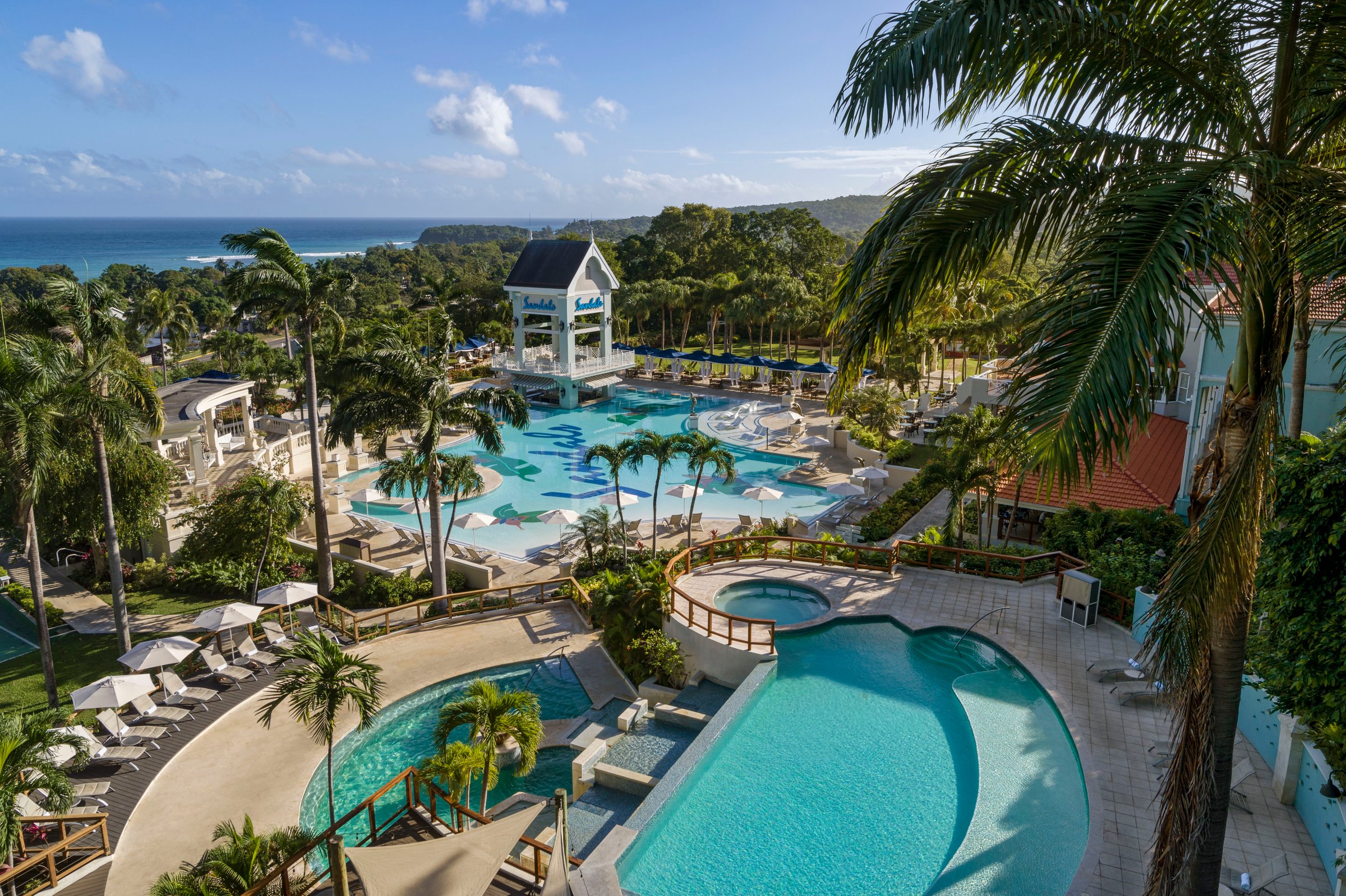Elevated view over the tiered main pools and gazebo toward the sea.
