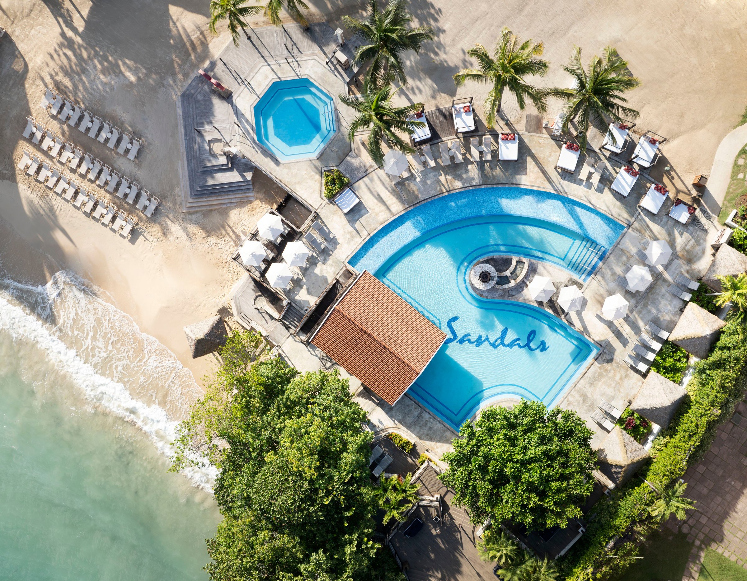 Top-down aerial of the Ochi Beach Club pool with the Sandals mosaic beside the beach.