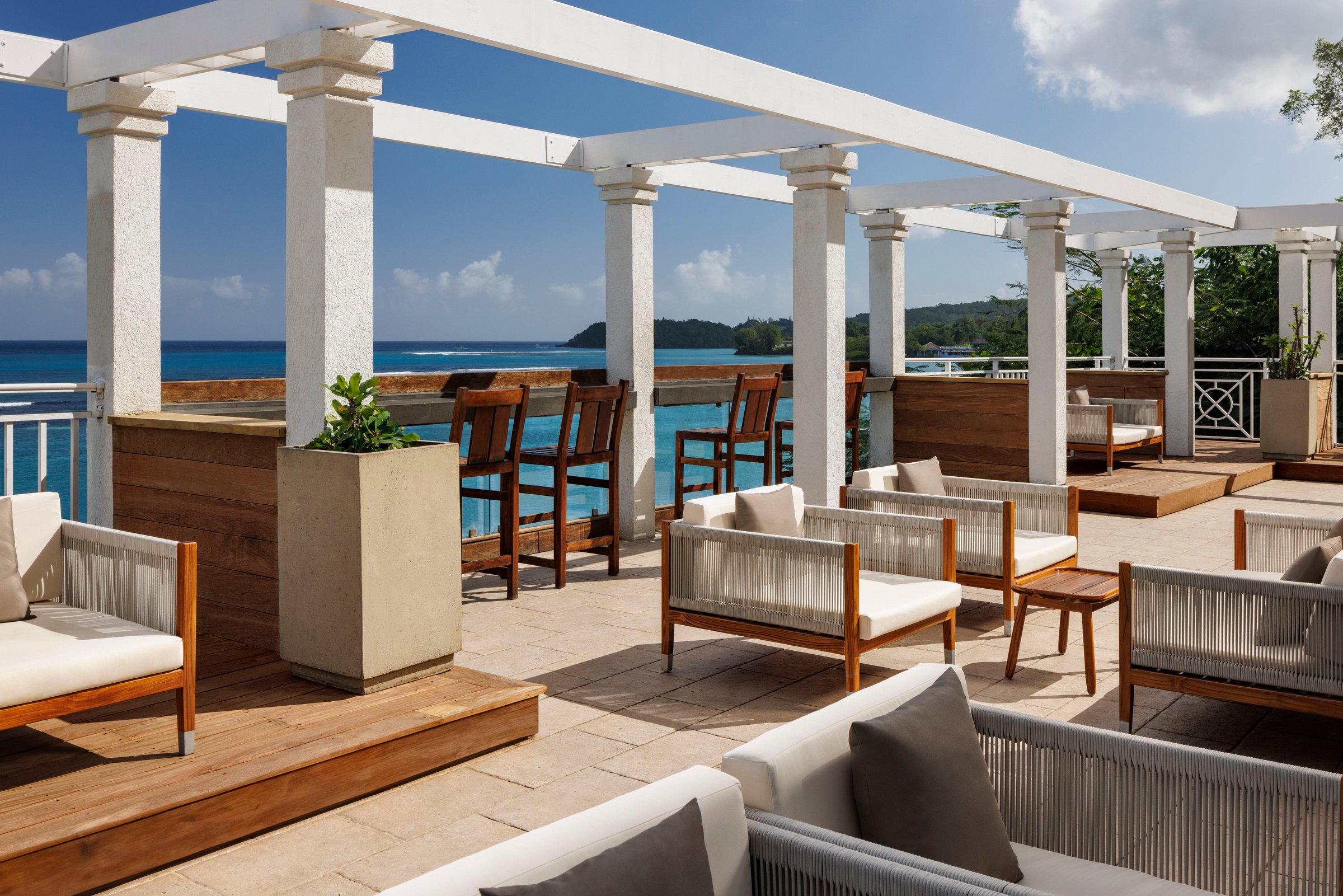 Rooftop bar terrace with white pergolas, lounge seating and sea views.