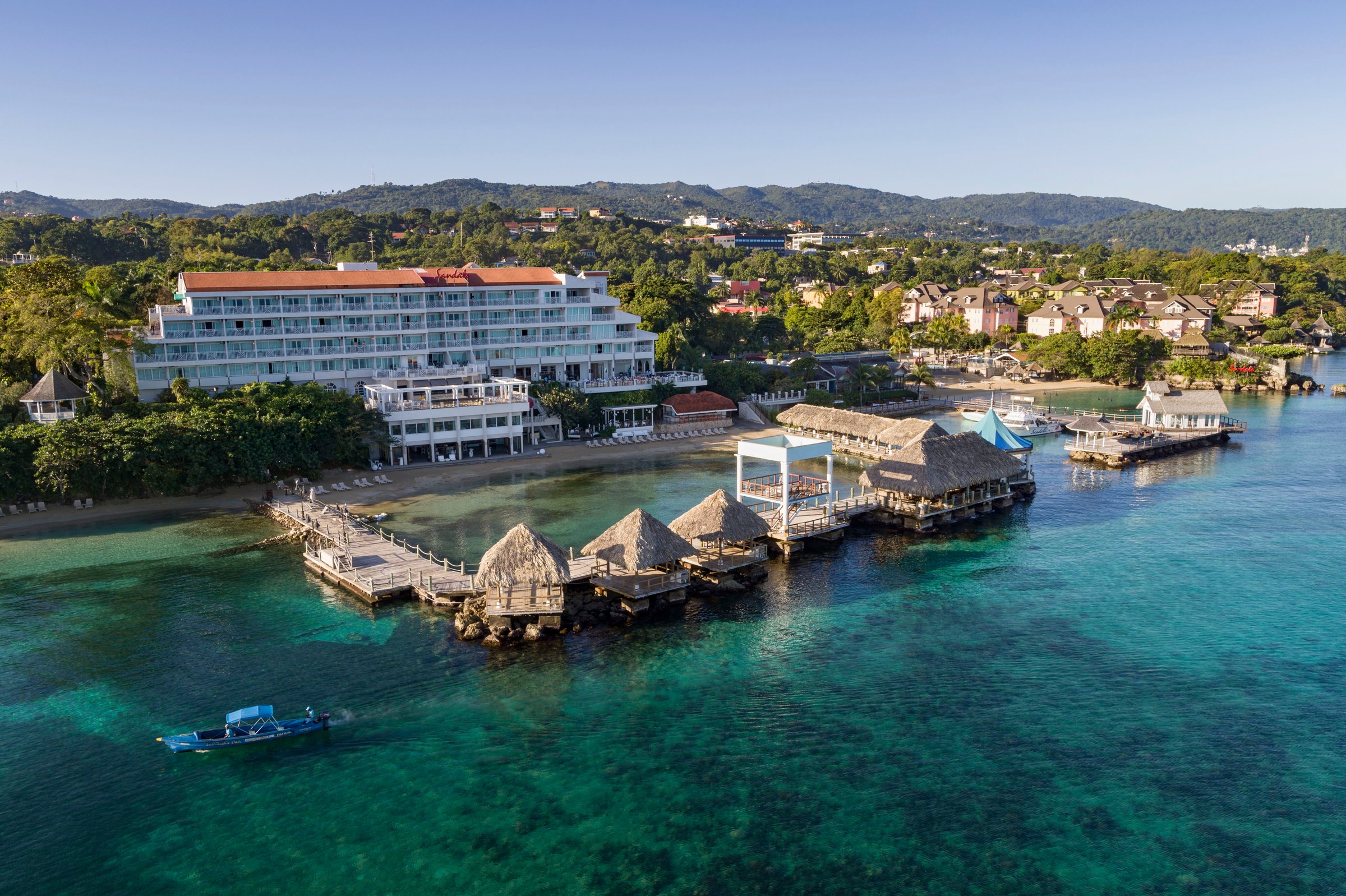 Aerial of the Riviera tower, overwater bungalows and piers on a clear bay.
