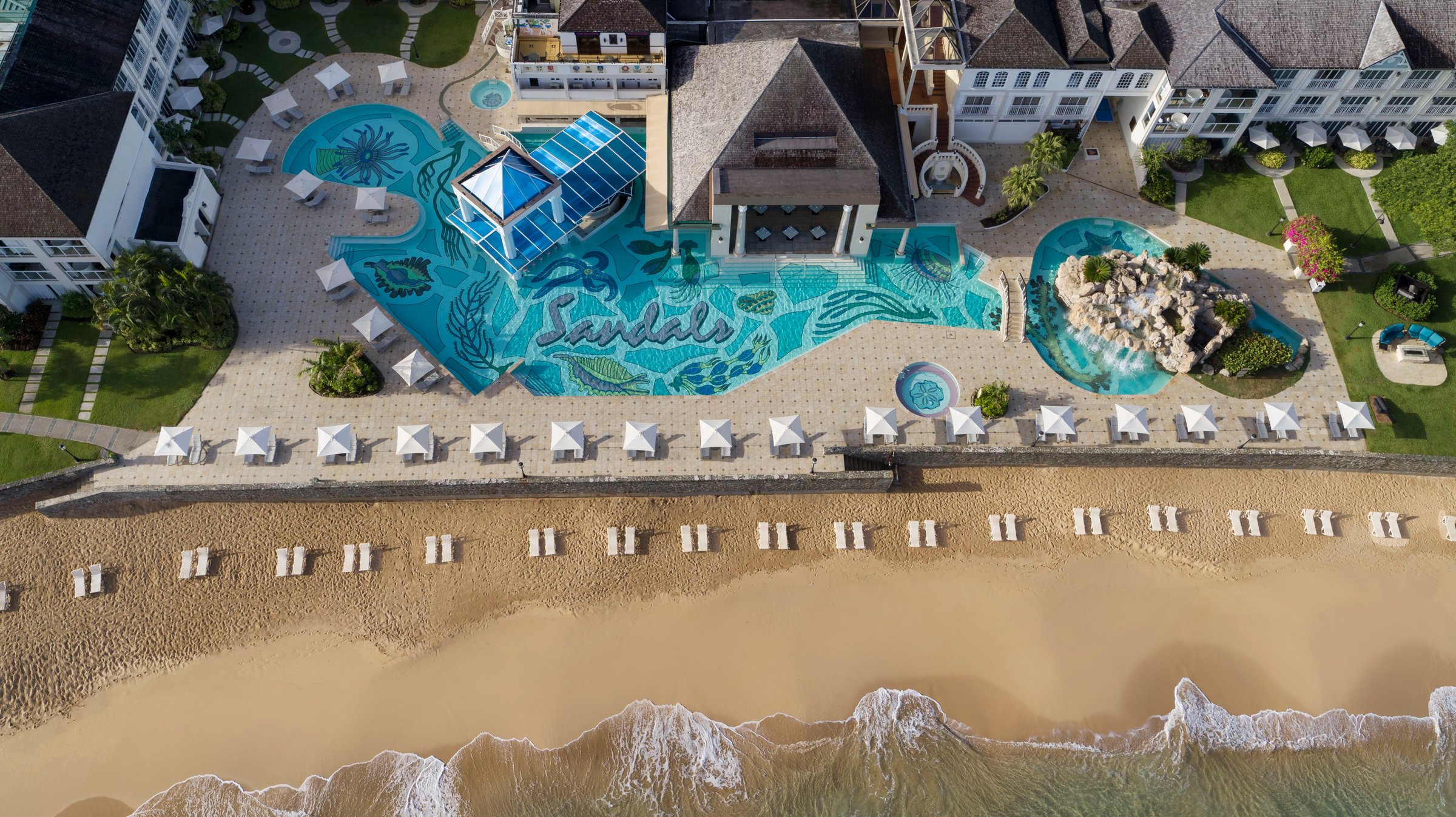 Top-down aerial of the main pool with the Sandals sea-life mosaic and swim-up bar.