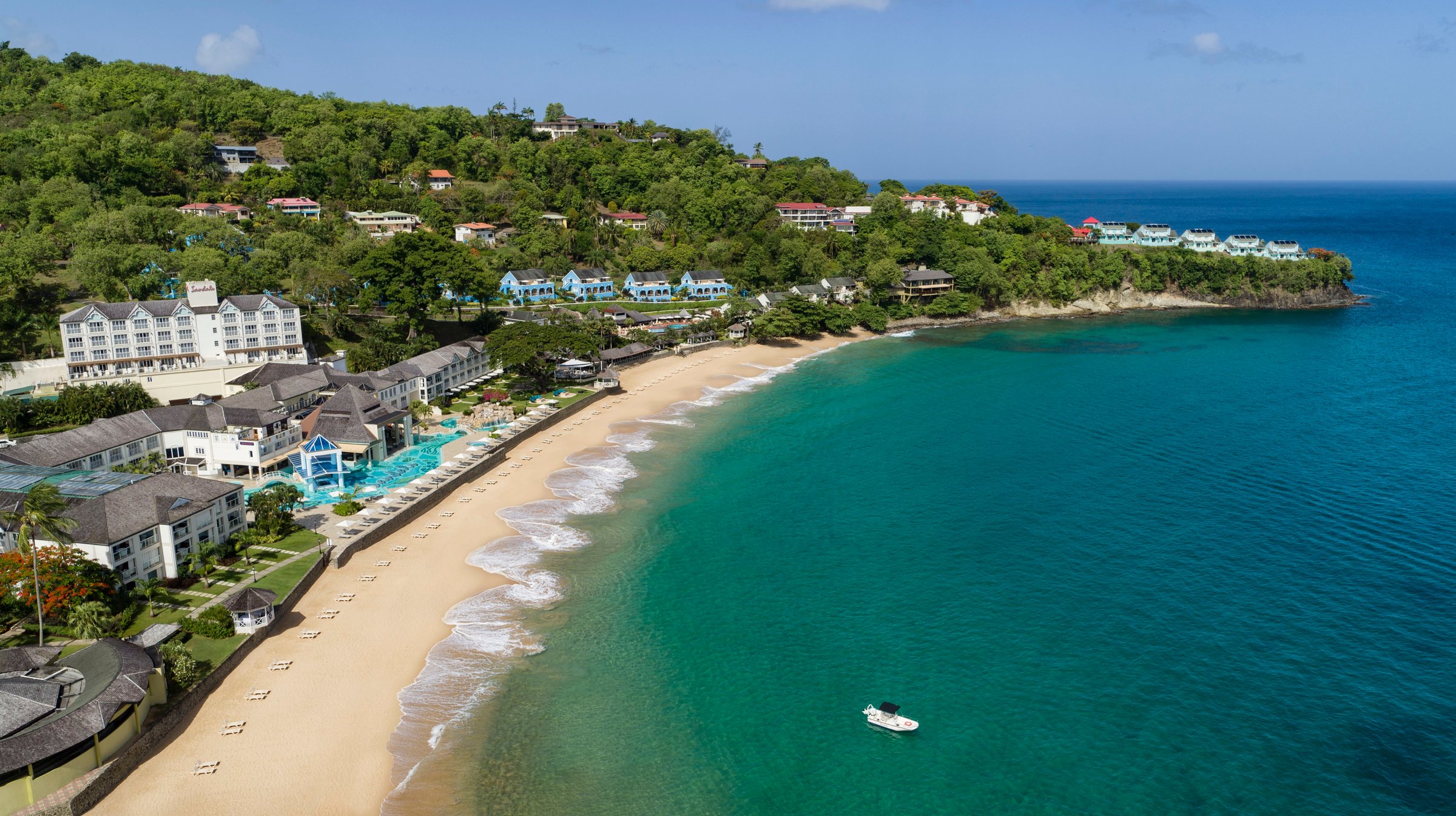 Aerial over the resort and sweeping beach on a turquoise bay.