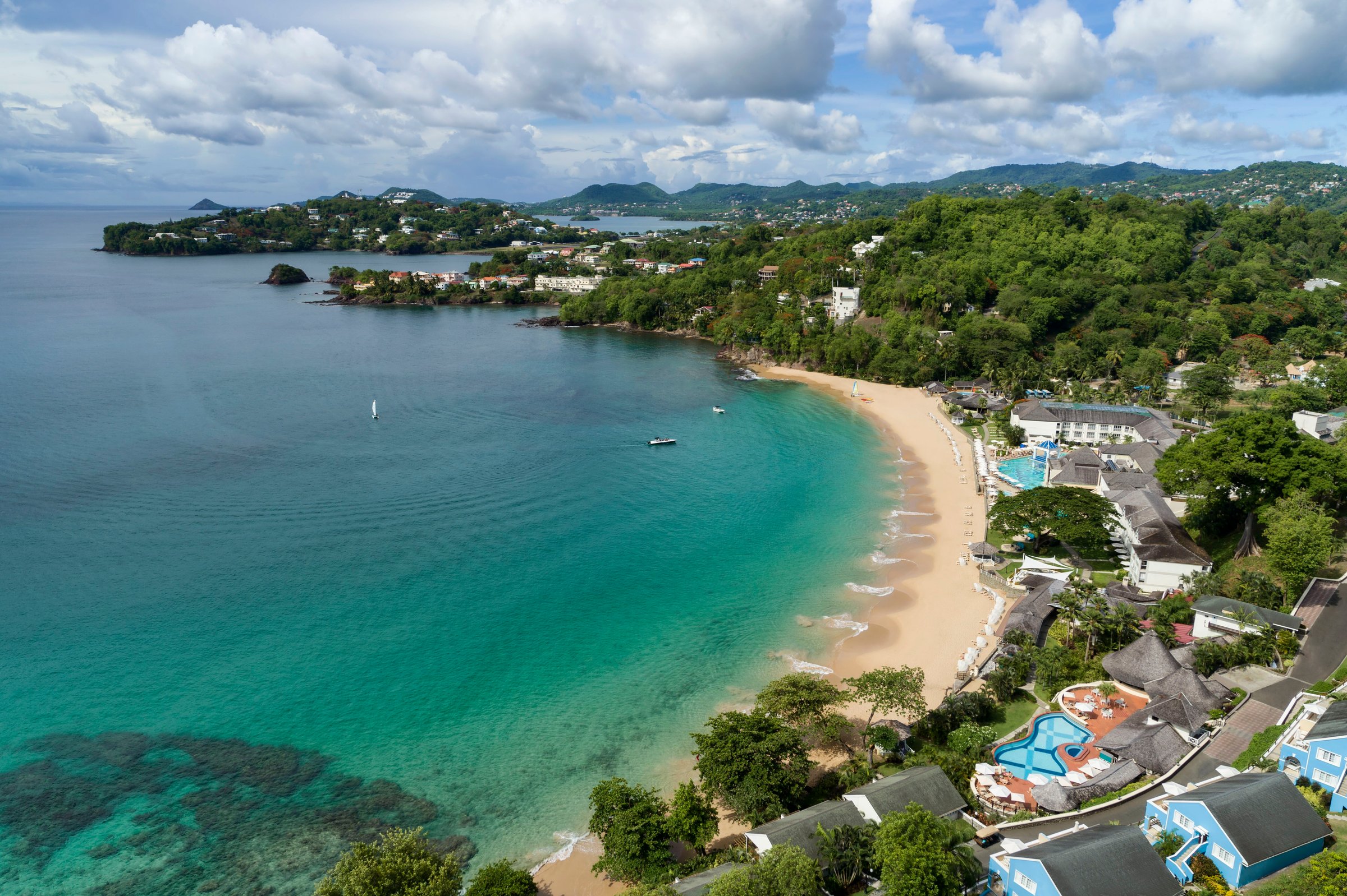 High aerial over the hillside suites and Pitons pool to the bay.