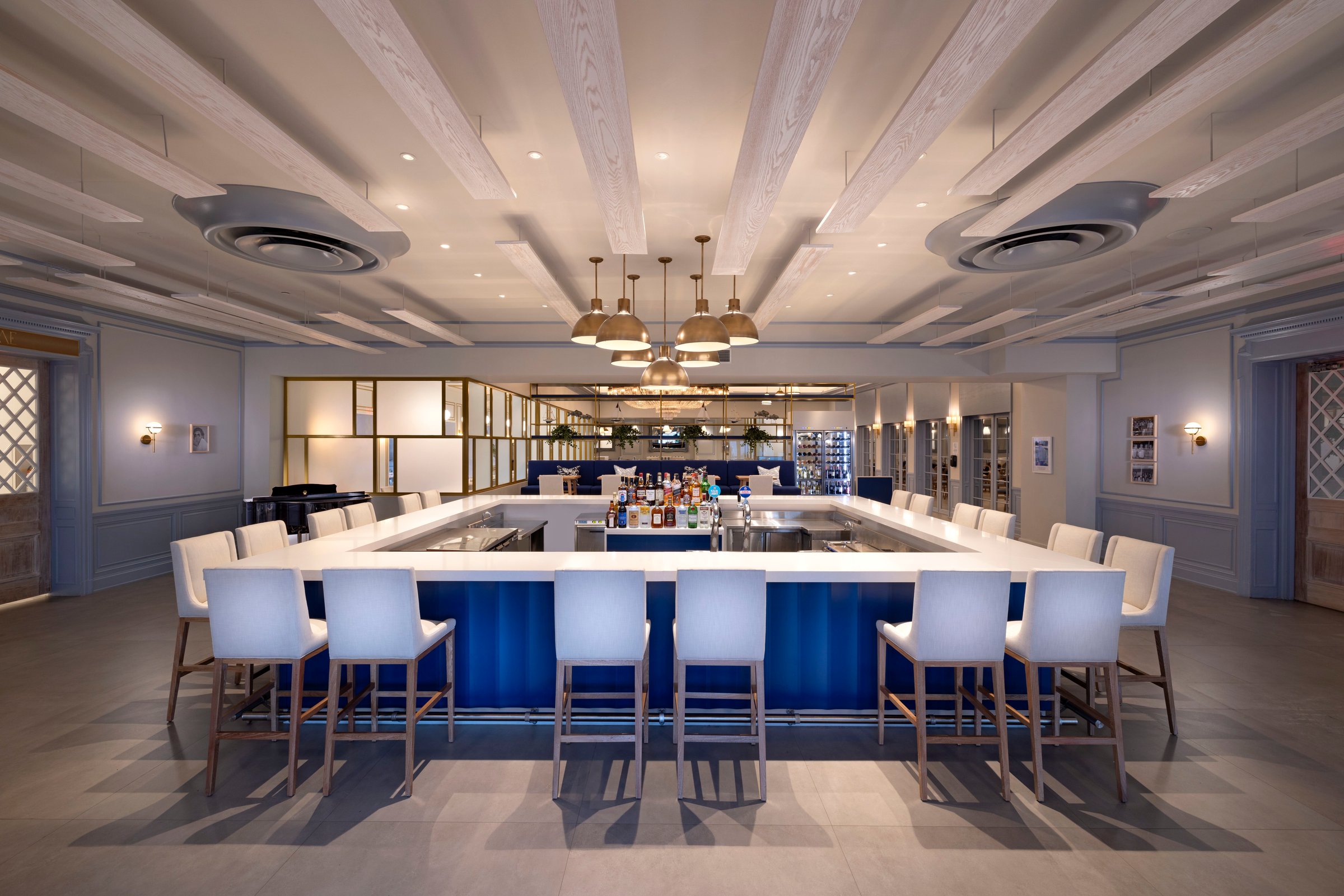 Bar at Butch's Chophouse with white stools around a blue counter.