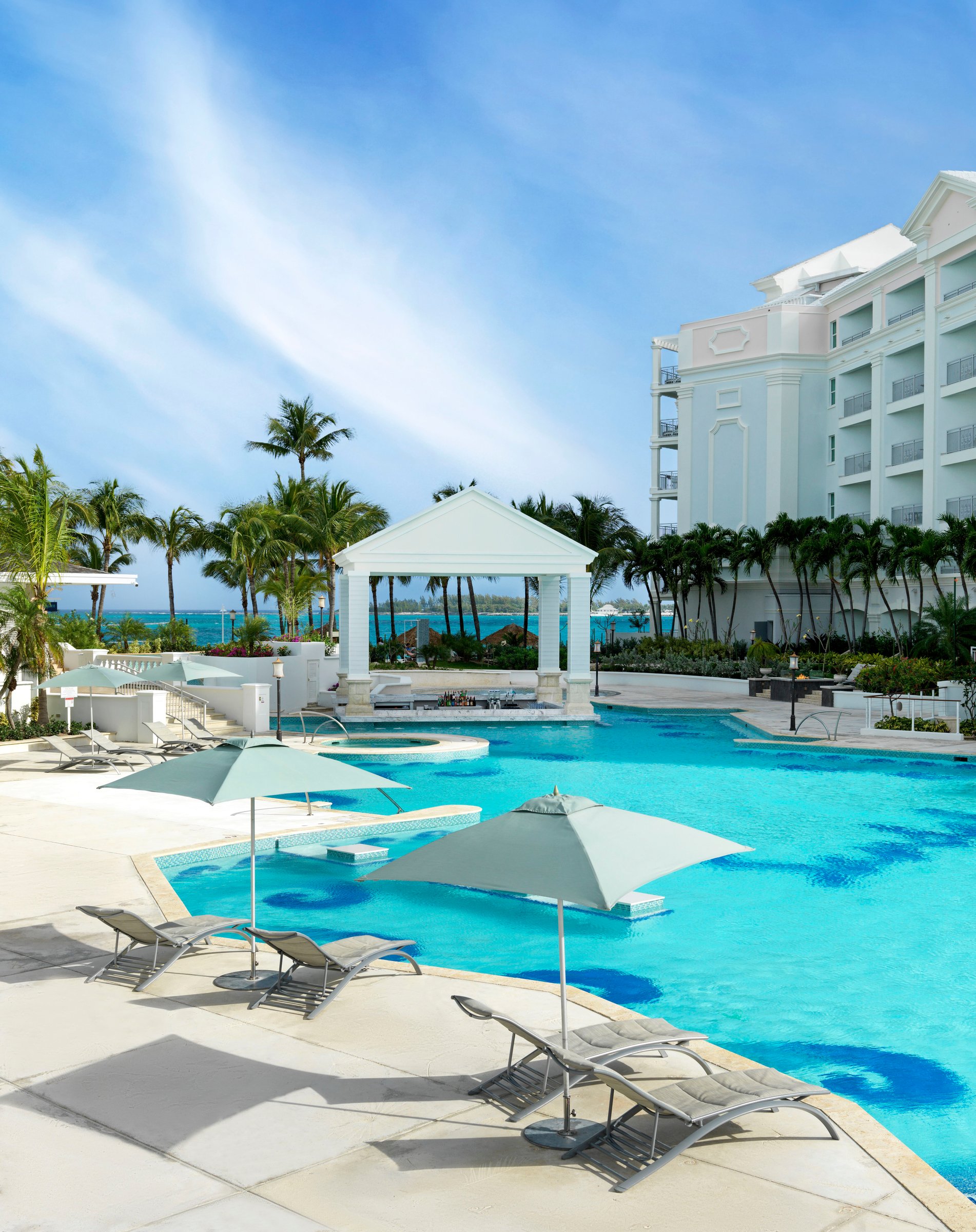 East Pool with its white gazebo, palms and the white resort tower under a bright blue sky.