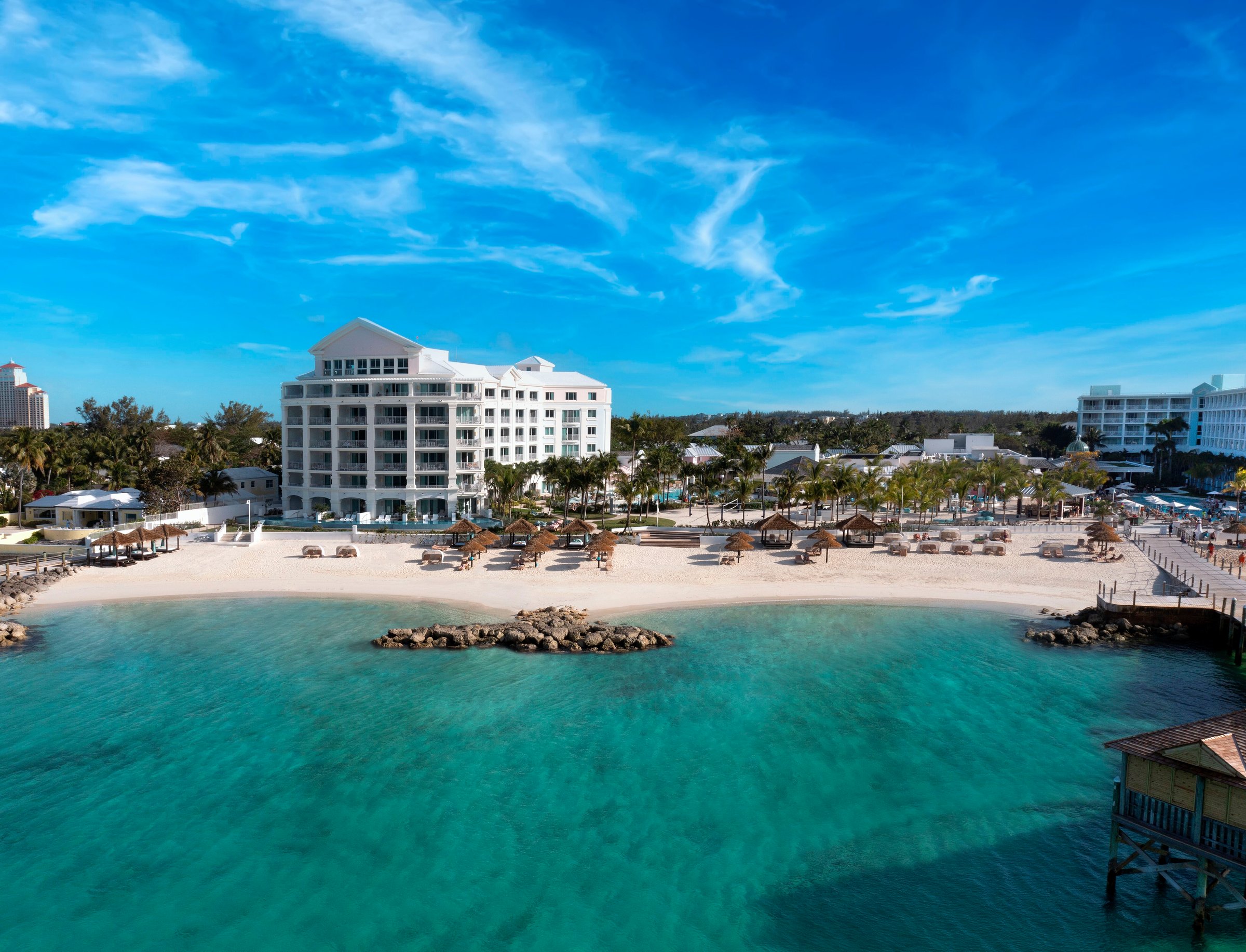 Aerial over the turquoise cove to the beach and the East Bay building.