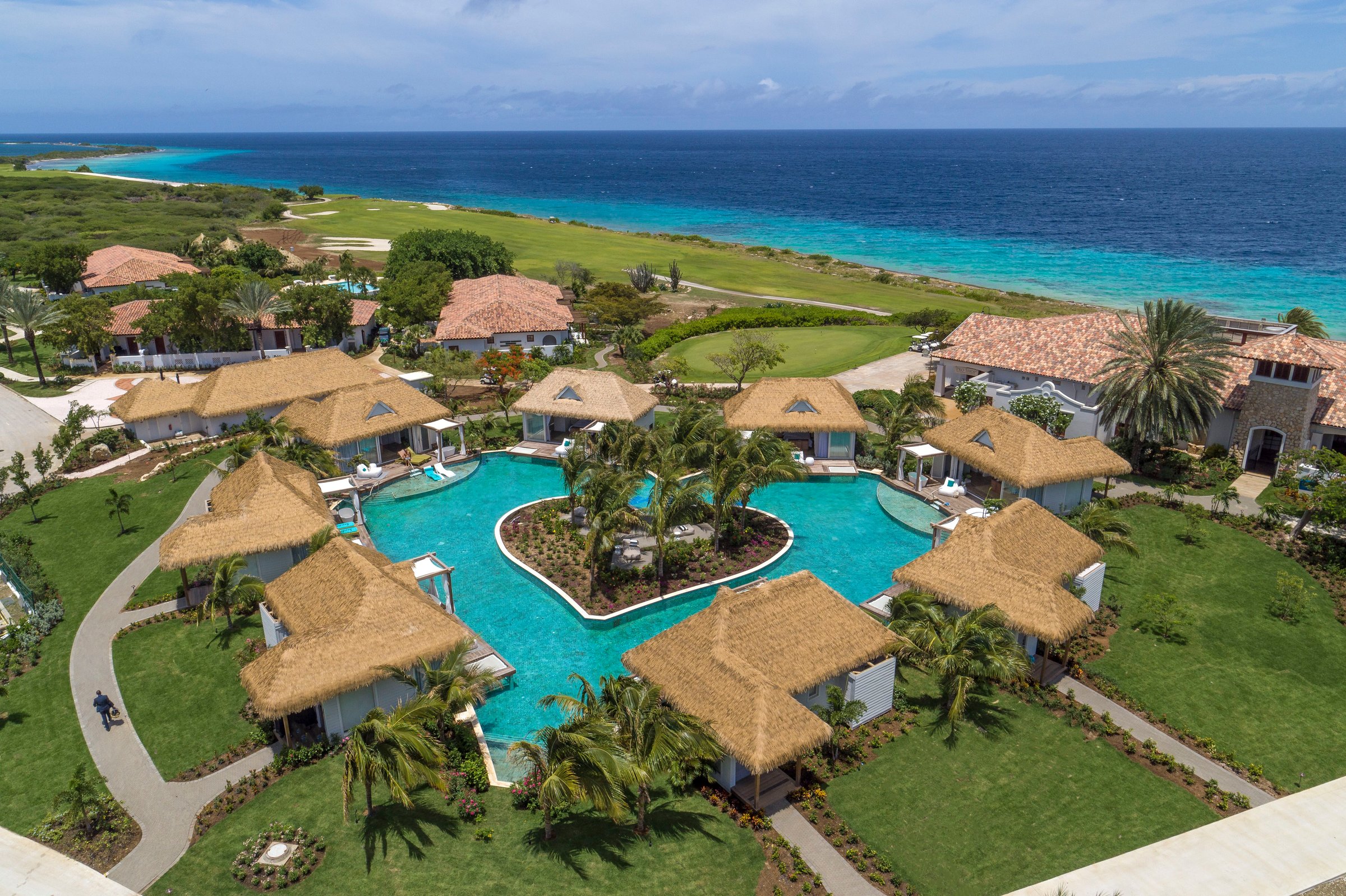 Aerial of the heart-shaped pool among thatched villas.