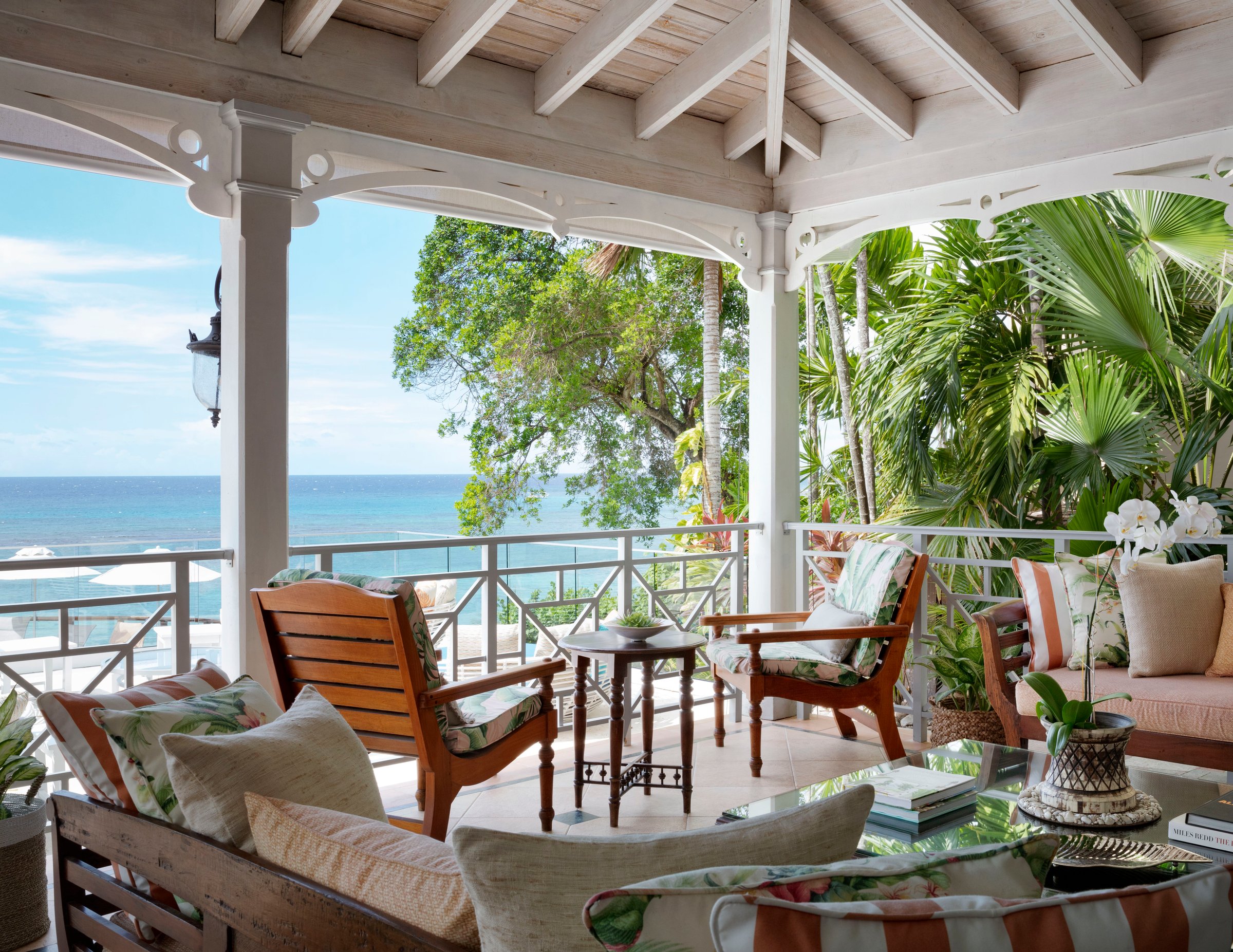 Veranda lounge with cushioned teak seating and a white rail over the sea.