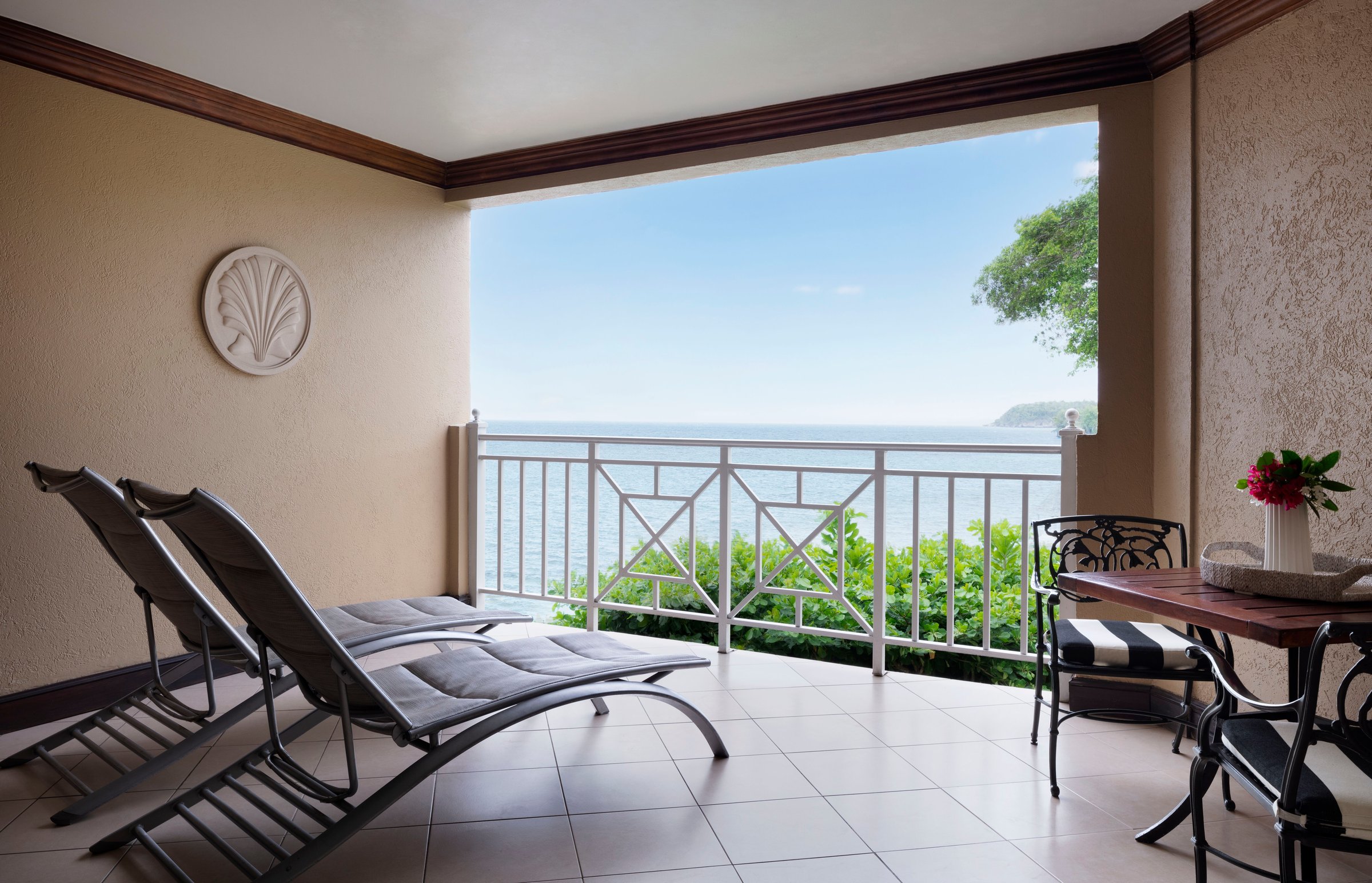 Shaded balcony with loungers and a bistro table facing the sea.