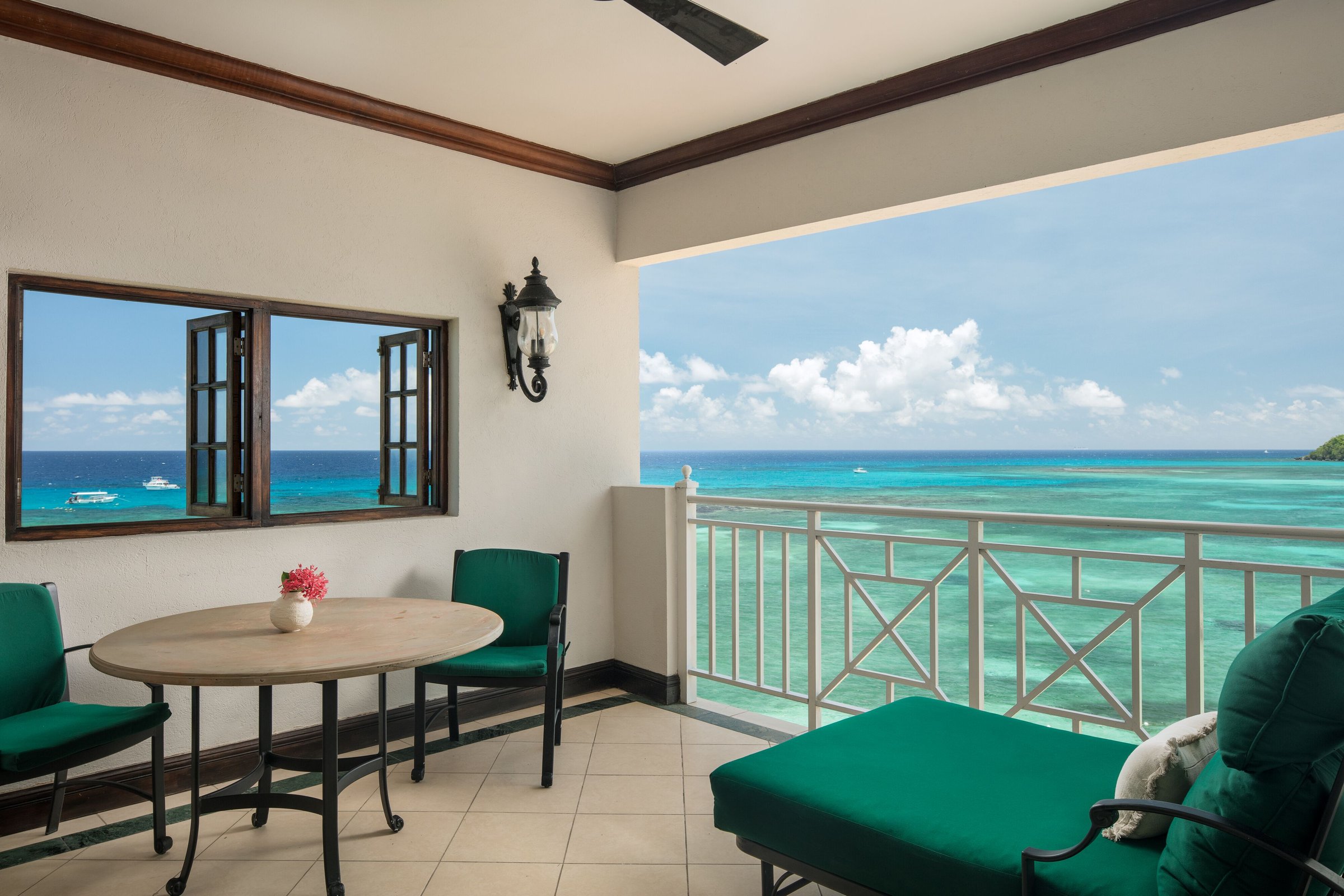 Suite terrace with green-cushioned seating above turquoise reef water.
