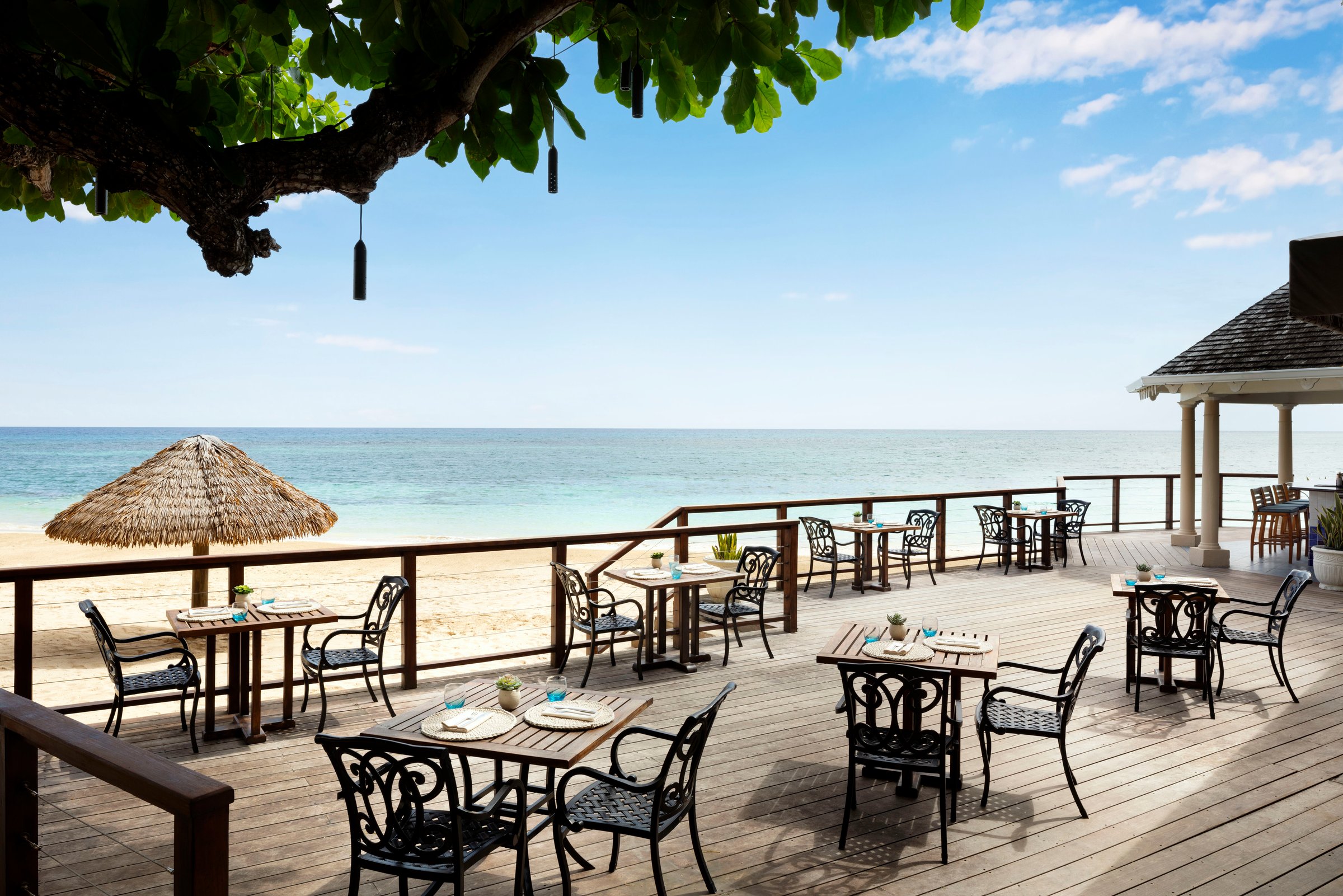 Royal Cafe beachfront deck dining under sea-grape branches.