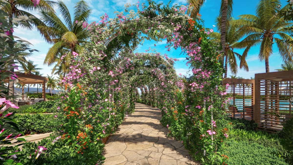 Flower-covered trellis archway with pink bougainvillea and palm trees at Sandals South Coast, lined with wooden pergolas and ocean view beyond.