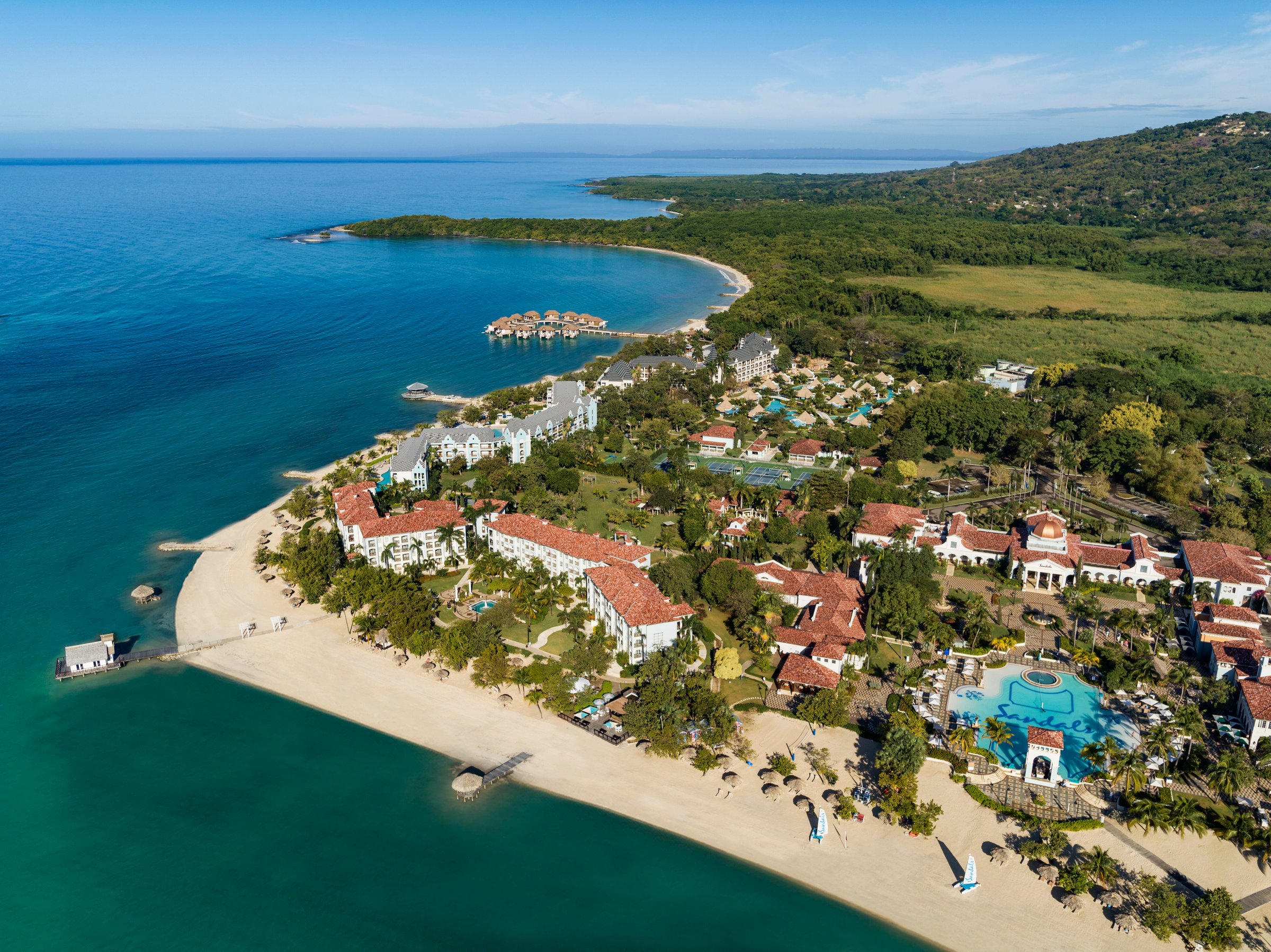 Aerial over the beach, main pool and over-water villa cove.