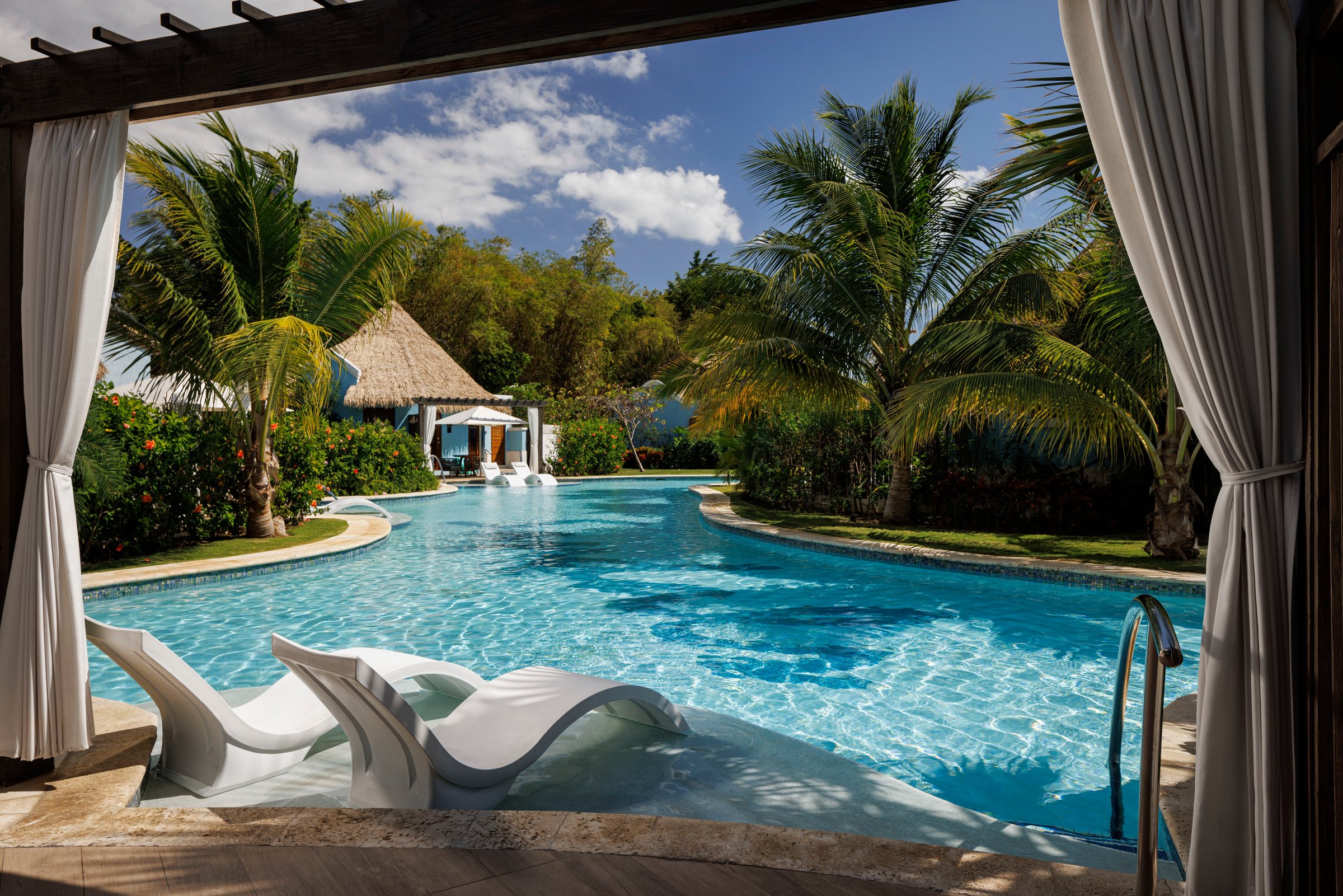 Swim-up suite patio with in-pool loungers on a palm-lined river pool.