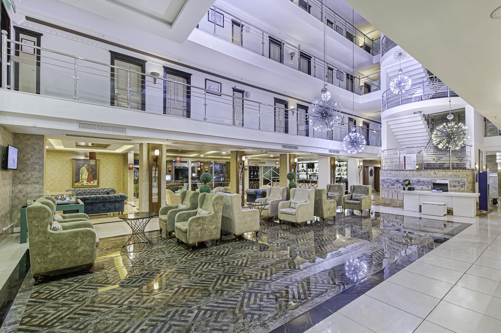 Multi-level atrium lounge at Sealife Family Resort Hotel with blue seating areas, patterned flooring, and decorative pendant lights overhead.