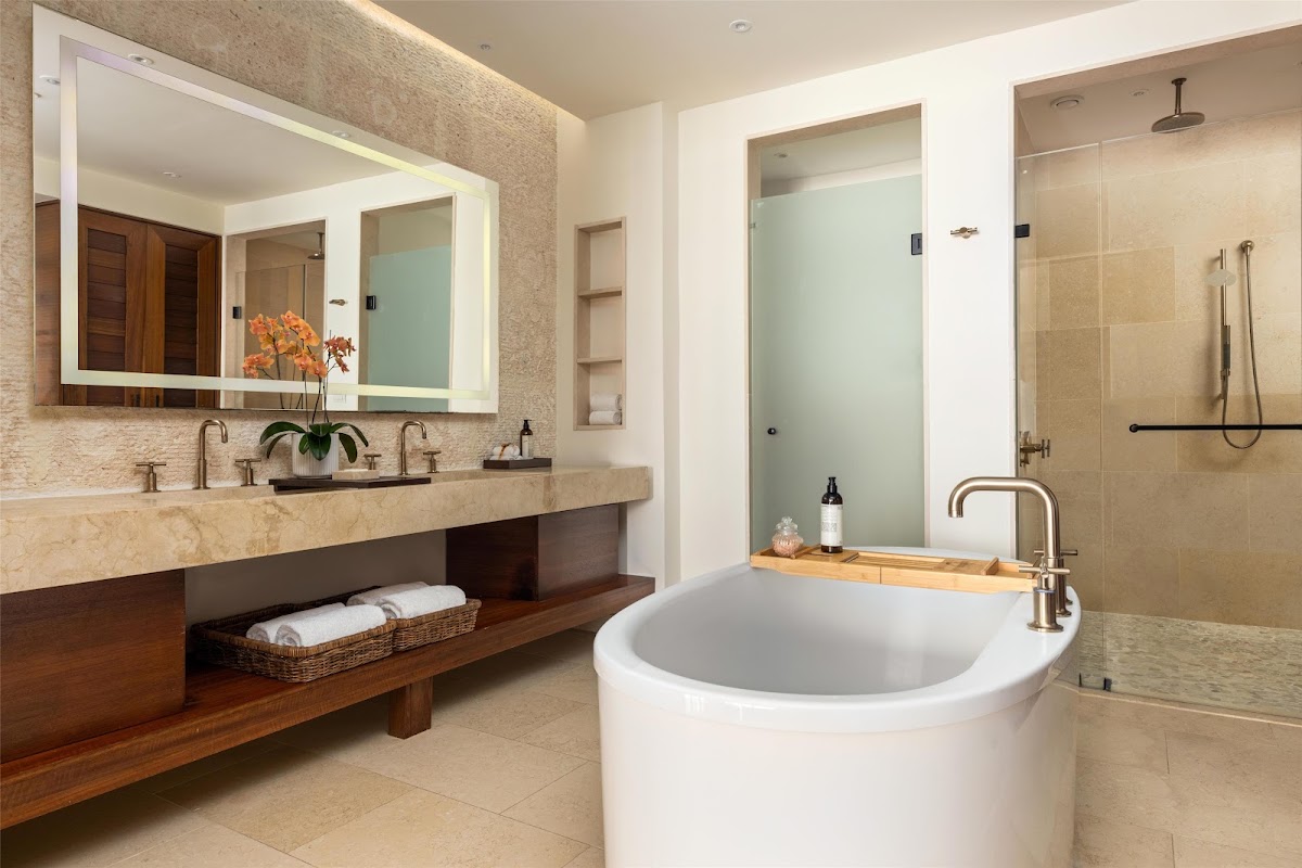 Spacious bathroom at Secrets Cap Cana Resort & Spa with soaking tub, dual vanity with illuminated mirror, and walk-in shower.