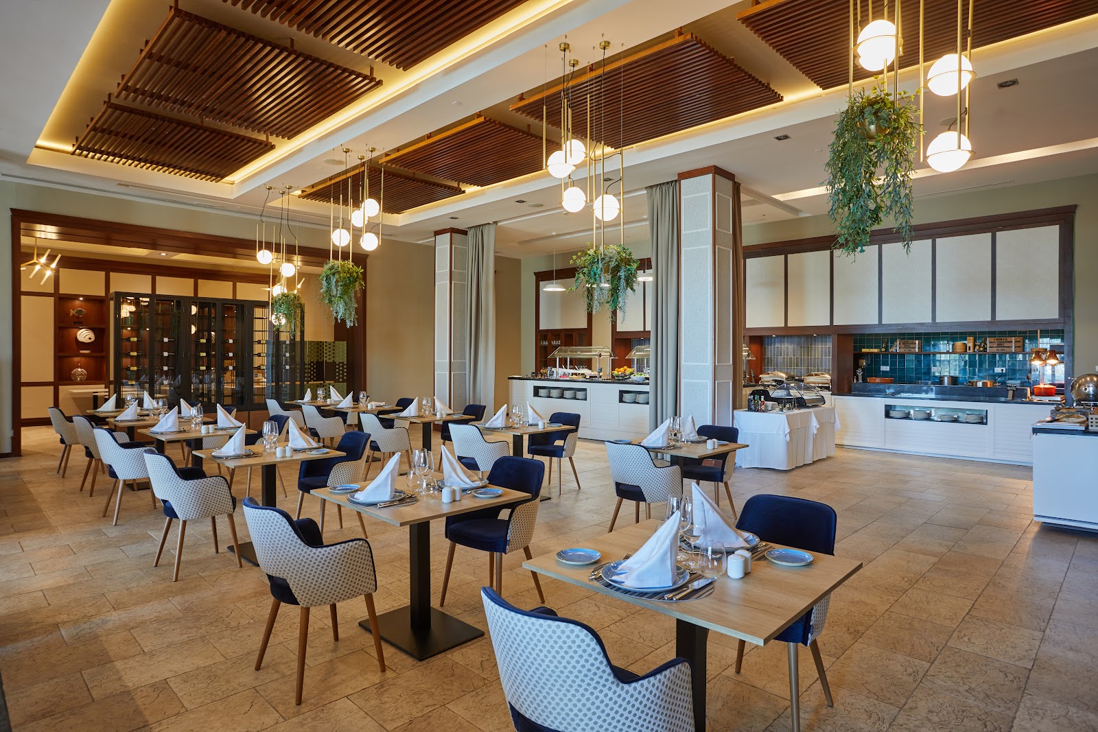 Beachfront dining area at Secrets Lanzarote Resort & Spa with woven chairs, round tables, wooden pergola, and ocean sunset view.