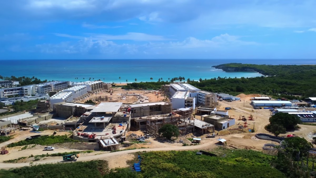 Aerial view of Secrets Macao Beach Punta Cana under construction with white resort buildings, turquoise ocean, and green coastline beyond.