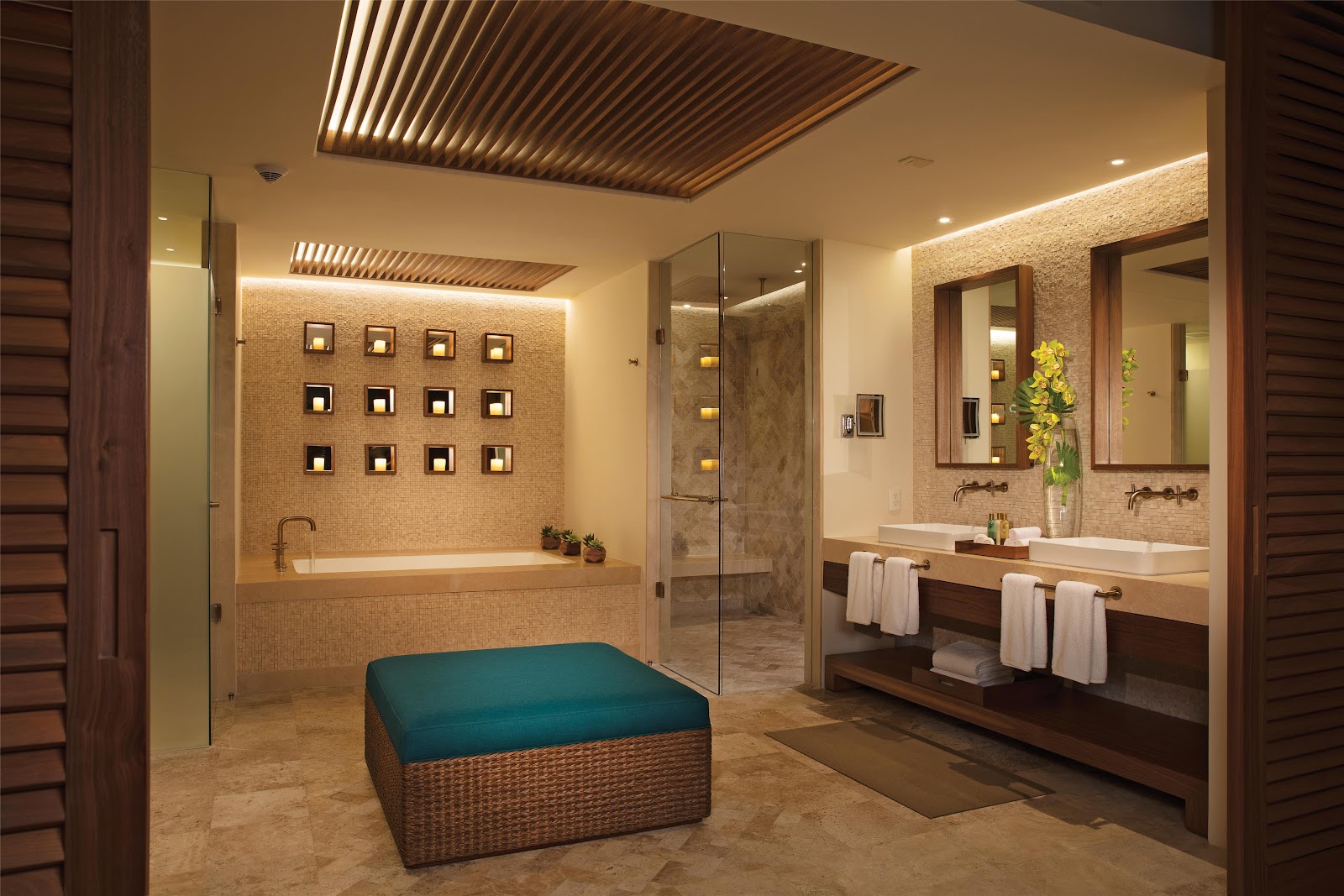 Luxury spa bathroom with dual vanities, soaking tub, walk-in shower, and woven ottoman seating at Secrets Maroma Beach Riviera Cancun.