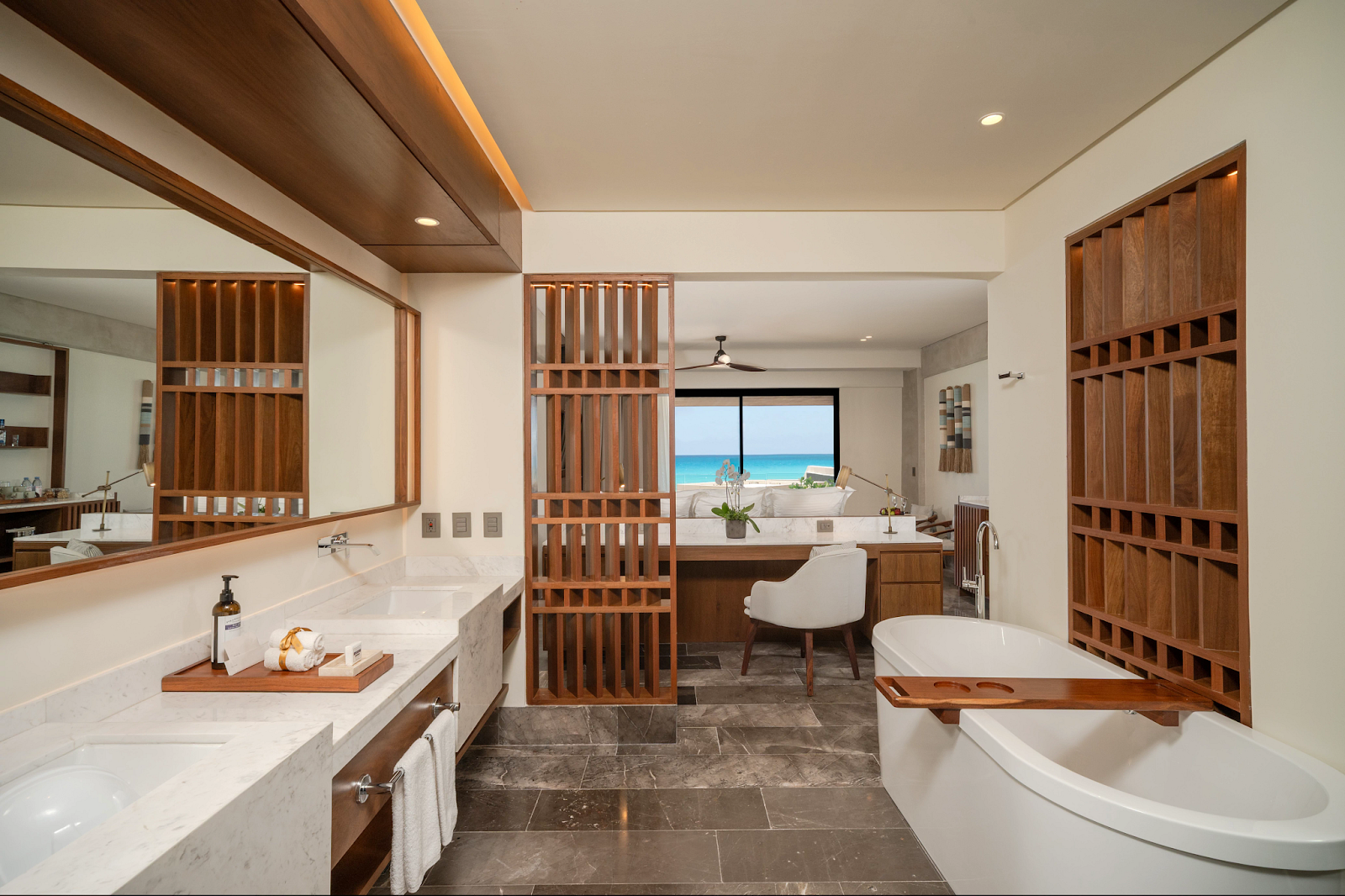 Spacious bathroom with dual sinks, soaking tub, and ocean view through wooden partition screens at Secrets Mirabel Cancun.