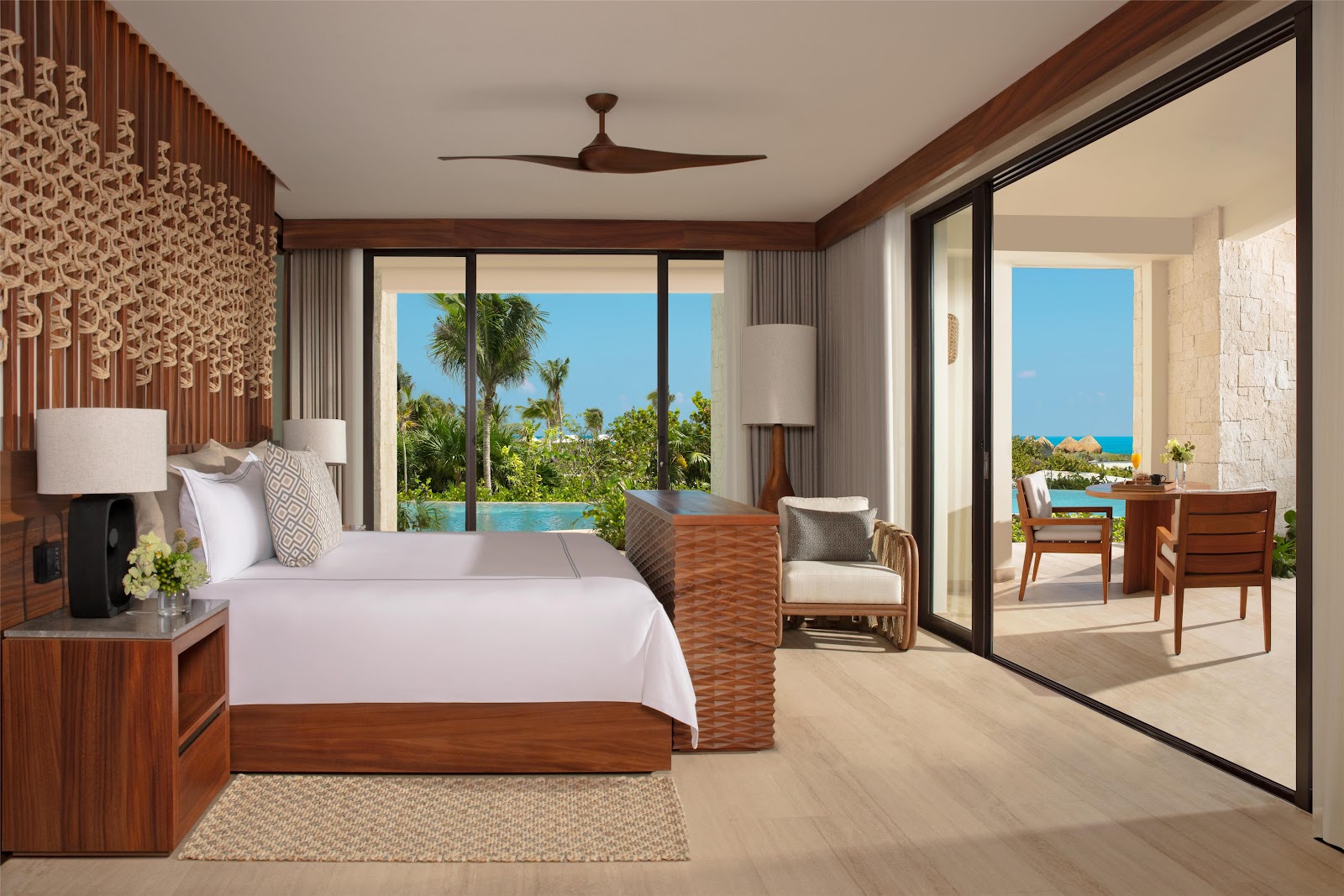 Spacious resort room at Secrets Playa Blanca Costa Mujeres with two queen beds, balcony doors, and ocean view visible through sheer curtains.