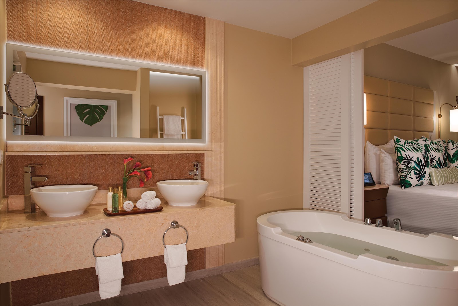 Spa-style bathroom with dual vessel sinks, illuminated mirror, soaking tub, and bedroom visible through open doors at Secrets Wild Orchid Montego Bay.