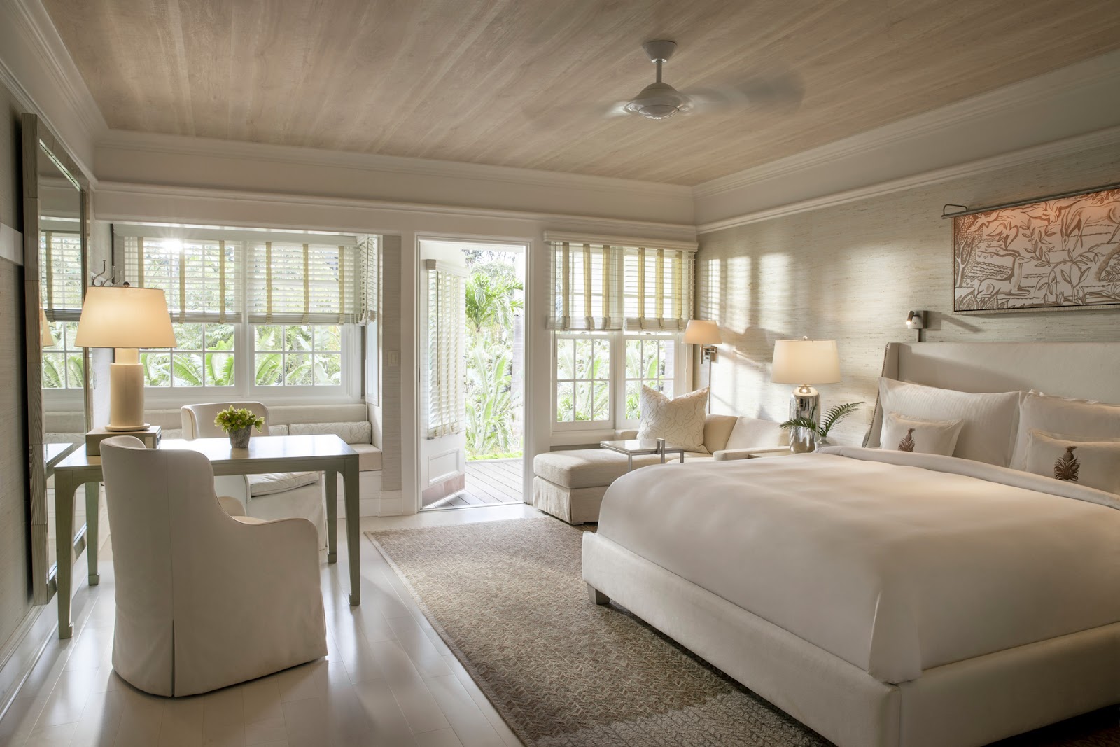 Bright suite interior with cream seating, round table, polished floors, and multiple windows overlooking greenery at Sensei Lanai.