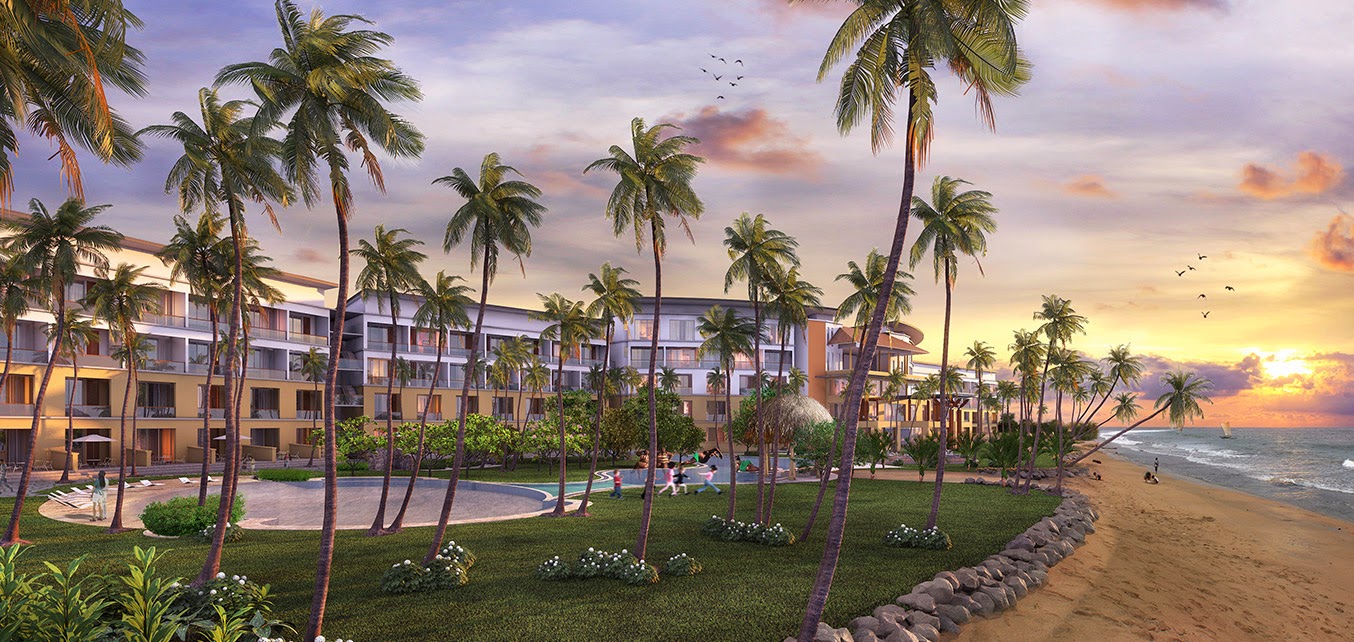 Sentido Heritance Negombo resort at sunset with palm-lined grounds, beachfront buildings, and guests on the sandy shore as birds fly overhead.