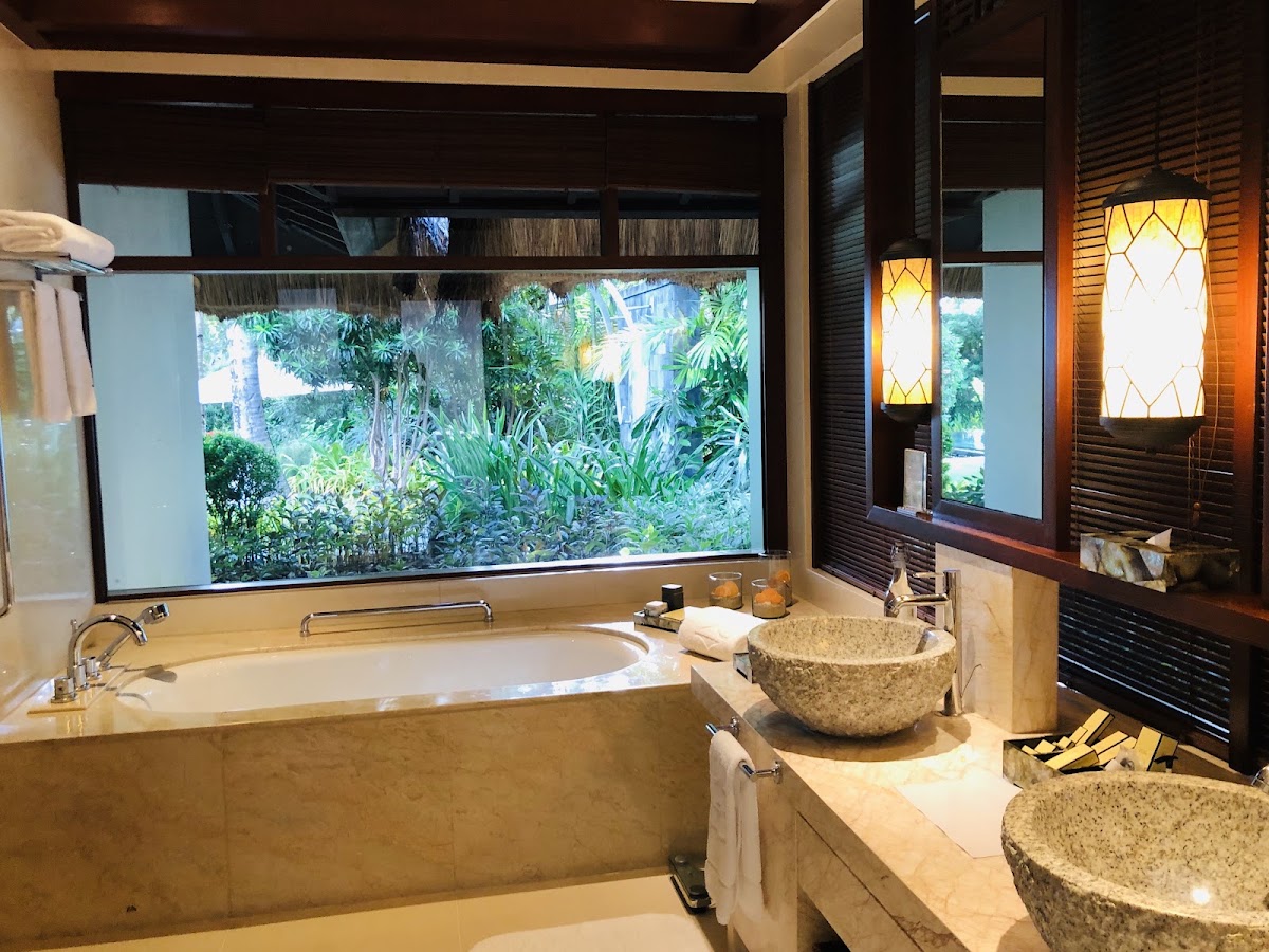 Luxury bathroom with sunken tub, stone vessel sinks, and large window overlooking tropical gardens at Shangri-La Boracay Resort & Spa.