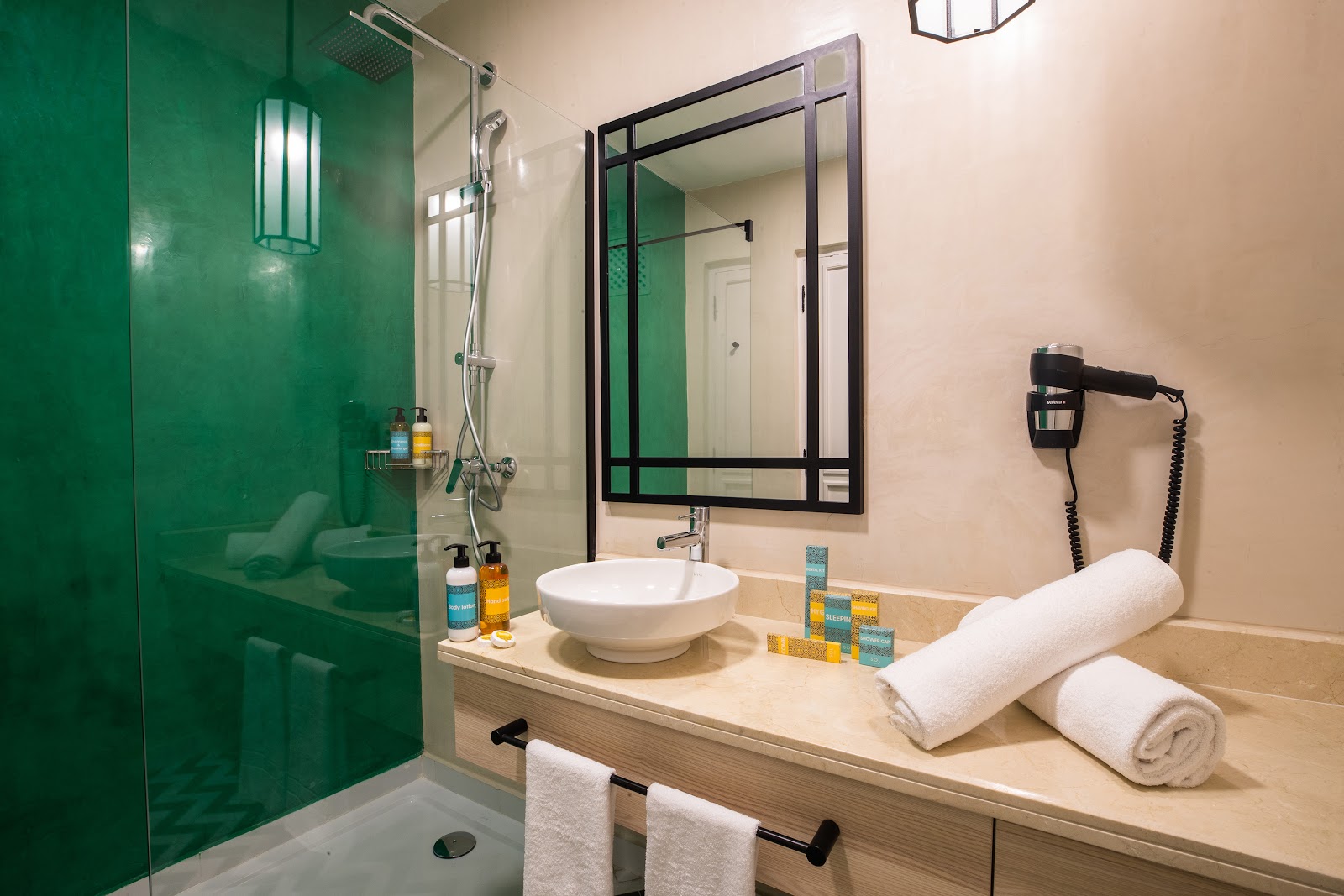 Stone spa room with sunken bathtub, arched alcoves holding golden vessels, rolled towel, and spa products on wooden tray at Sol Oasis Marrakech.
