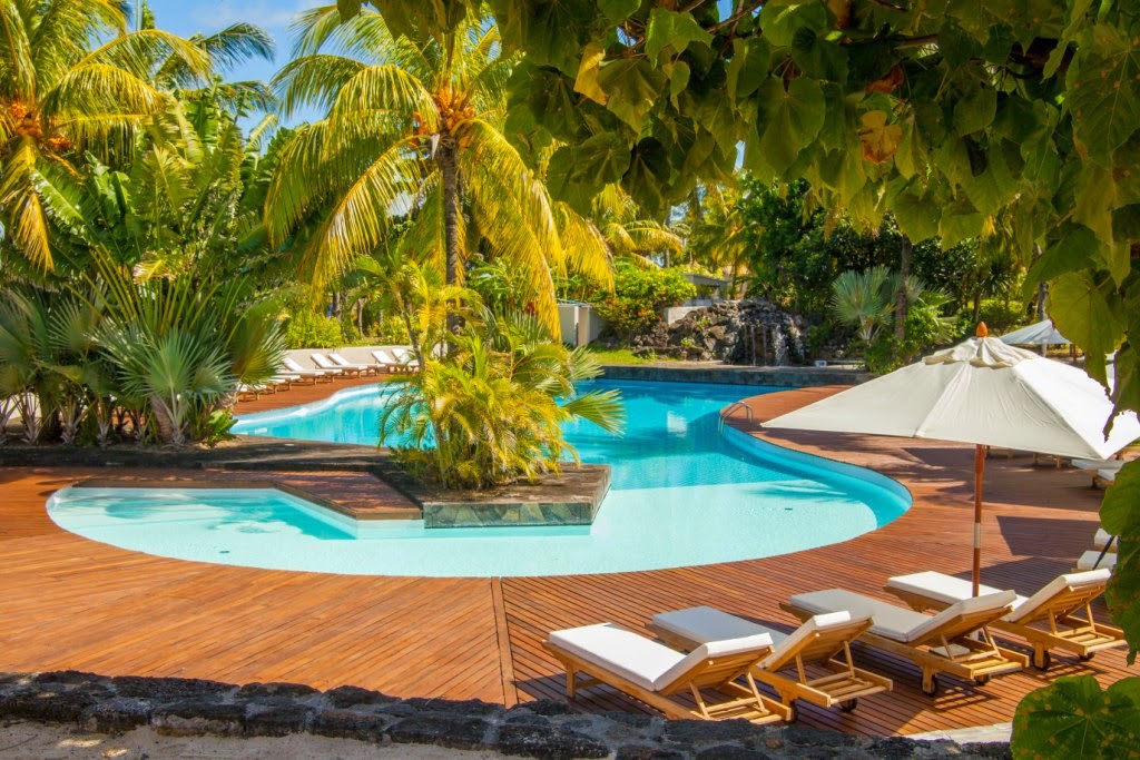 Wooden deck with turquoise pool, palm trees, and white umbrellas beside loungers at Solana Beach Mauritius.