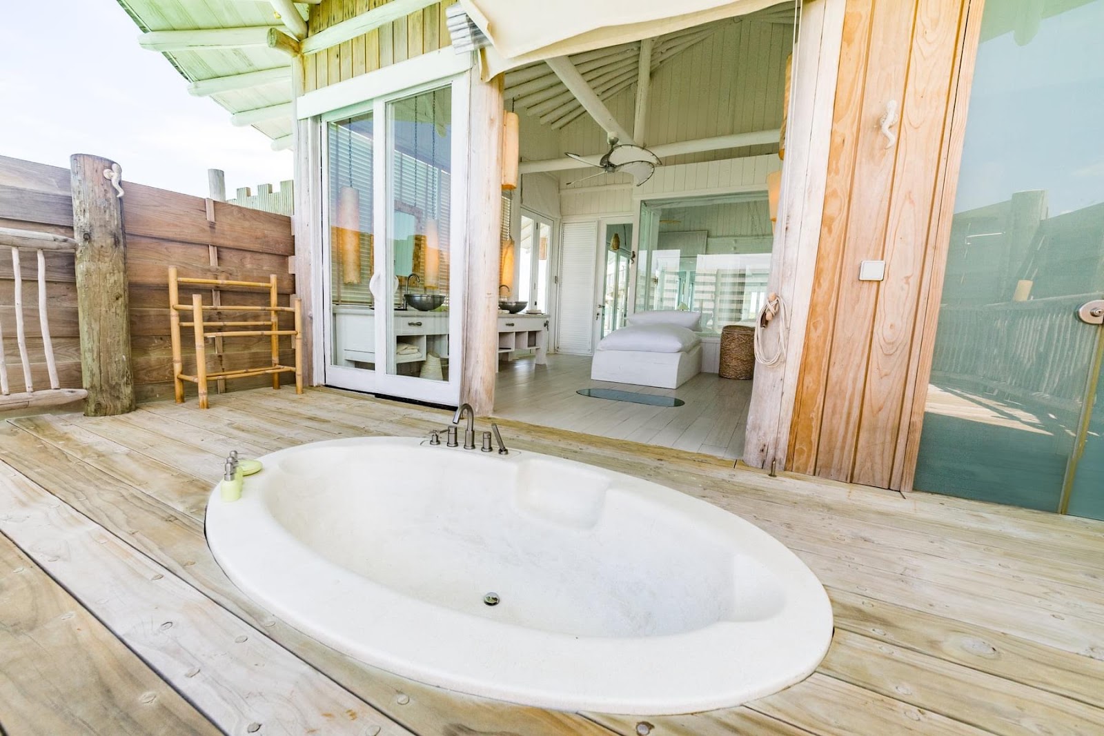 Oval soaking tub on a wooden deck overlooking the bedroom and ocean at Soneva Jani.