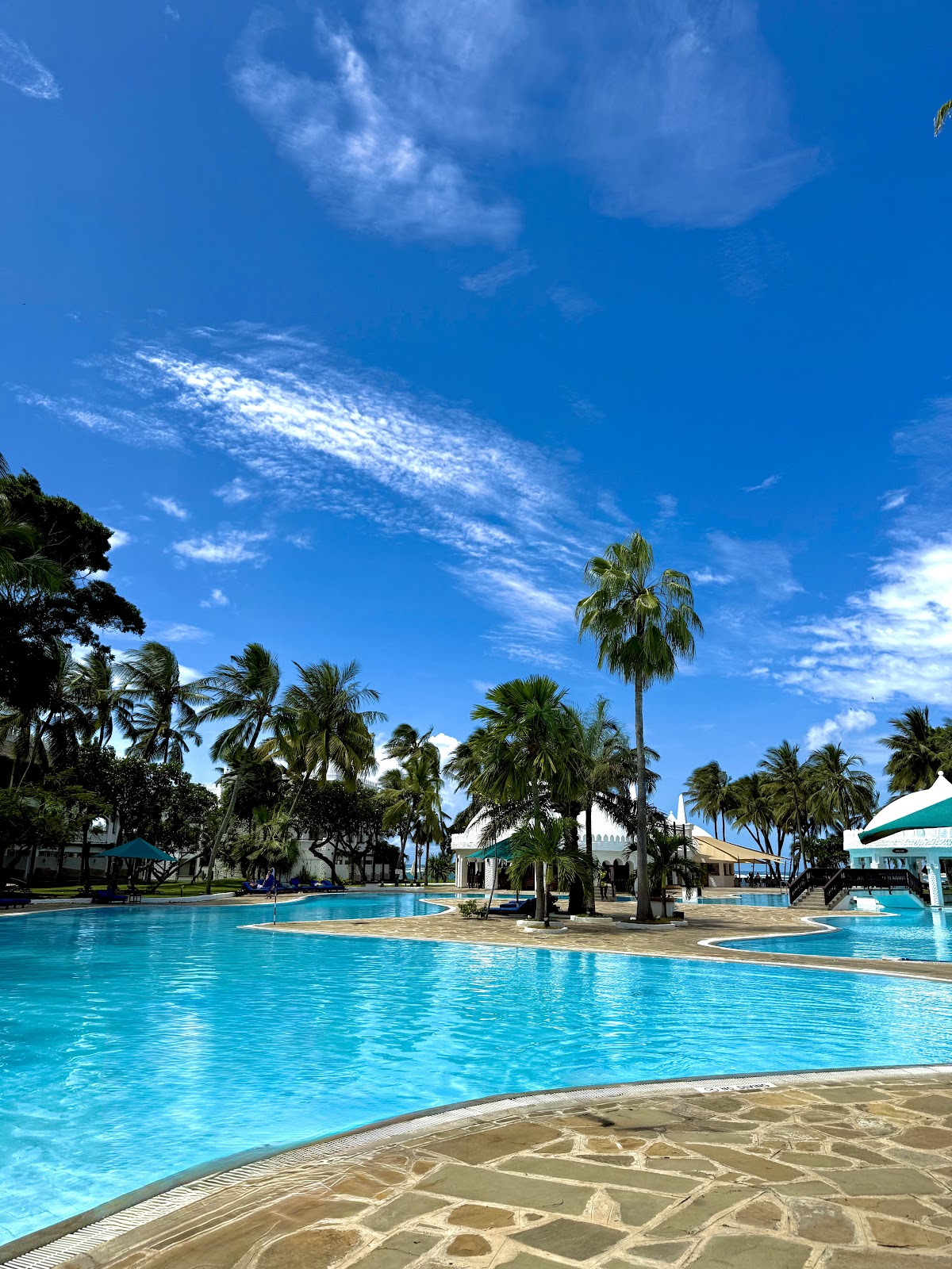 Large lagoon-style pool with palm trees and sandy islands under blue sky at Southern Palms Beach Resort.